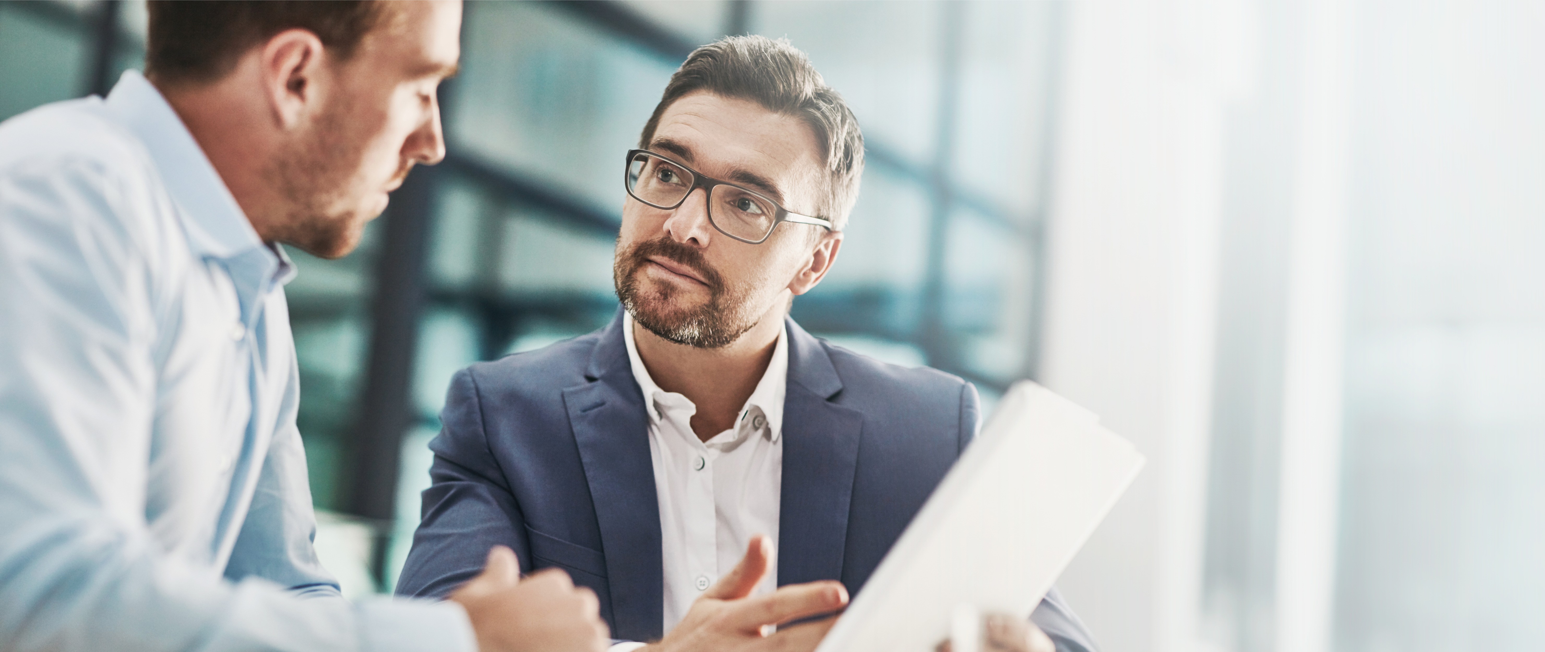 a group of people sitting around a table with laptops