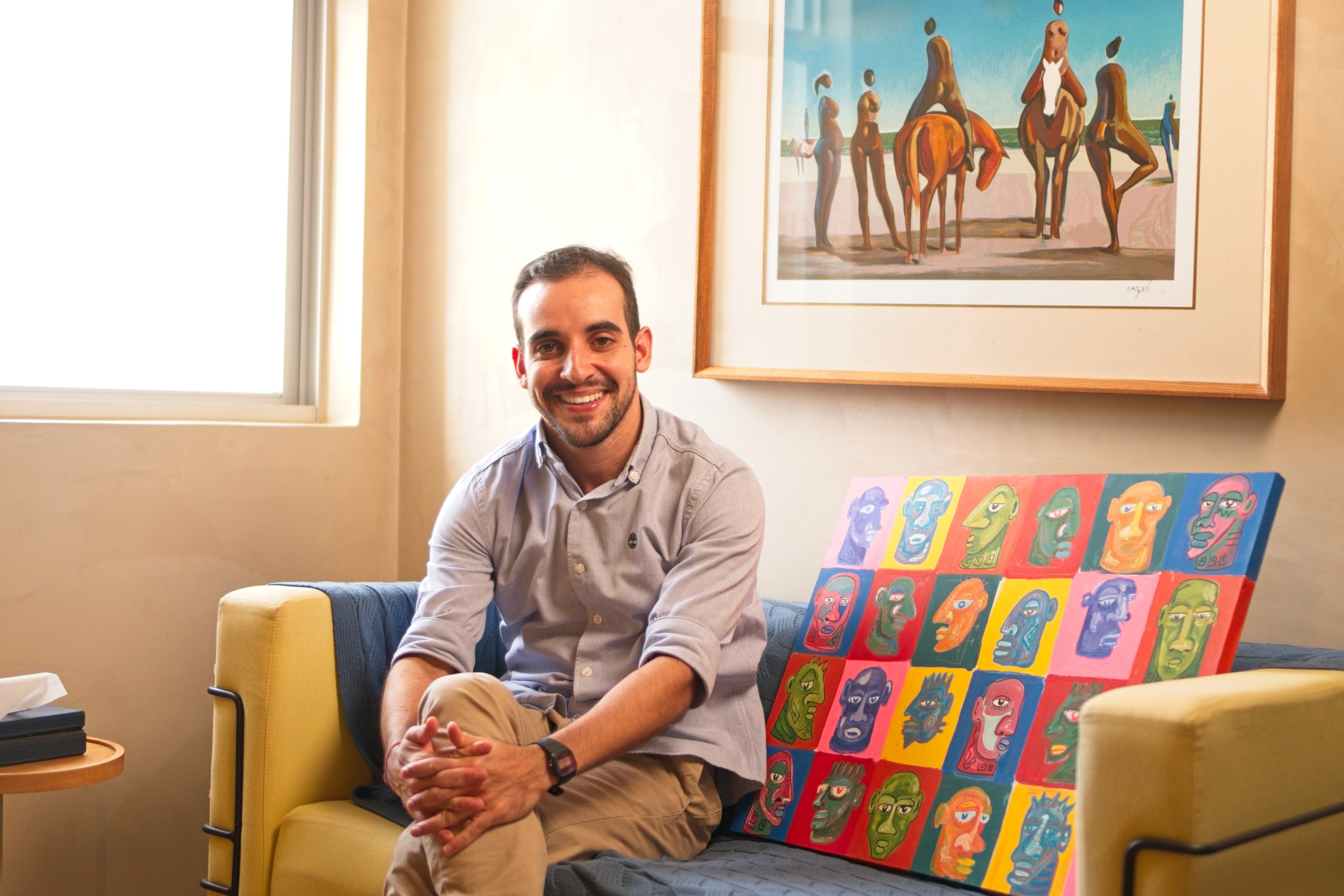 A person with curly hair sits at a desk, working on a laptop in a cozy, well-lit environment.