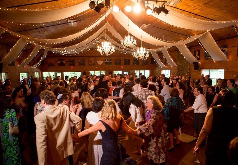 Guests dancing under draped lights and chandeliers in the lodge at Camp Lenox