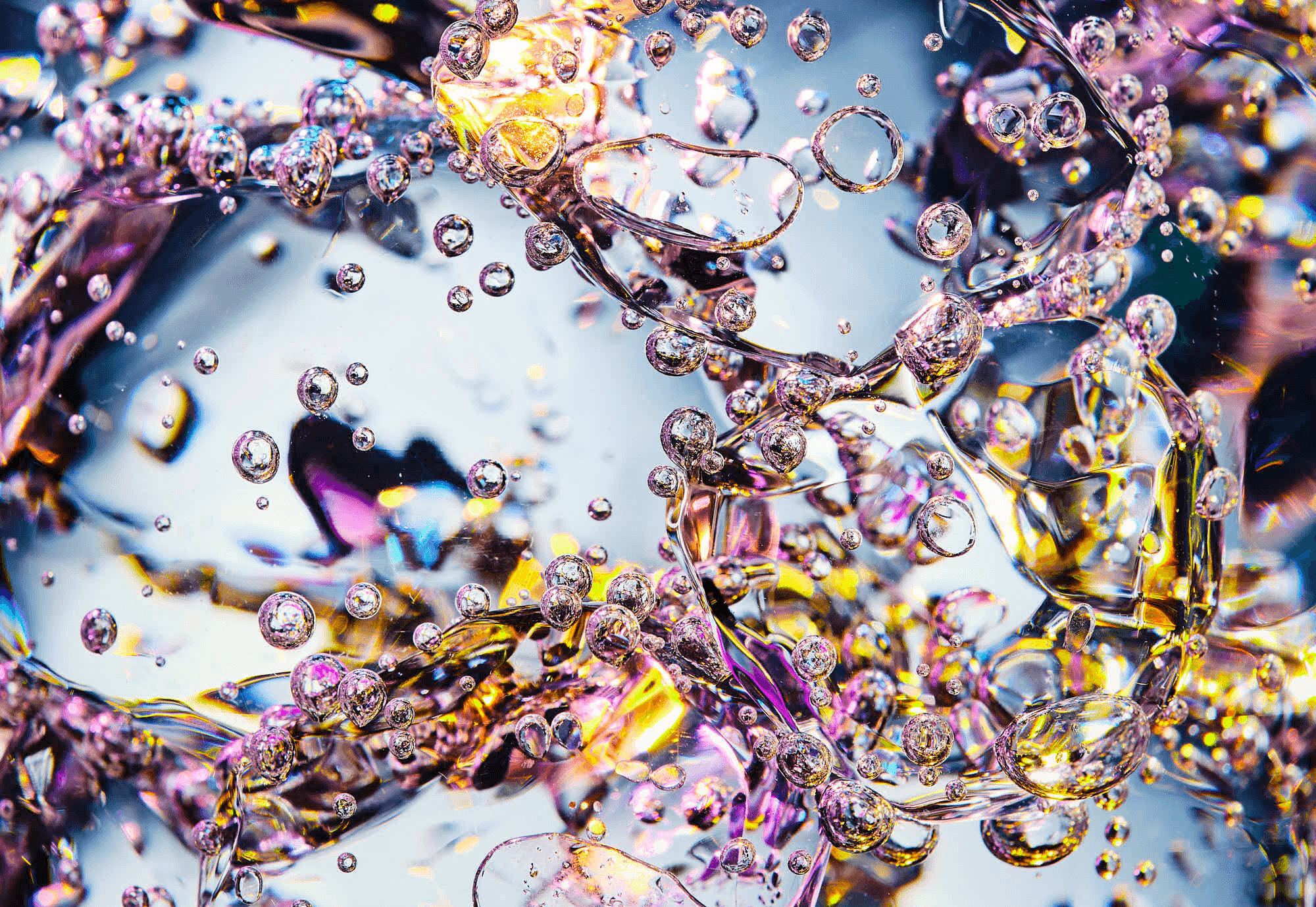Abstract close-up of textured ice surfaces with bubbles and vibrant colors of purple, gold, and blue.