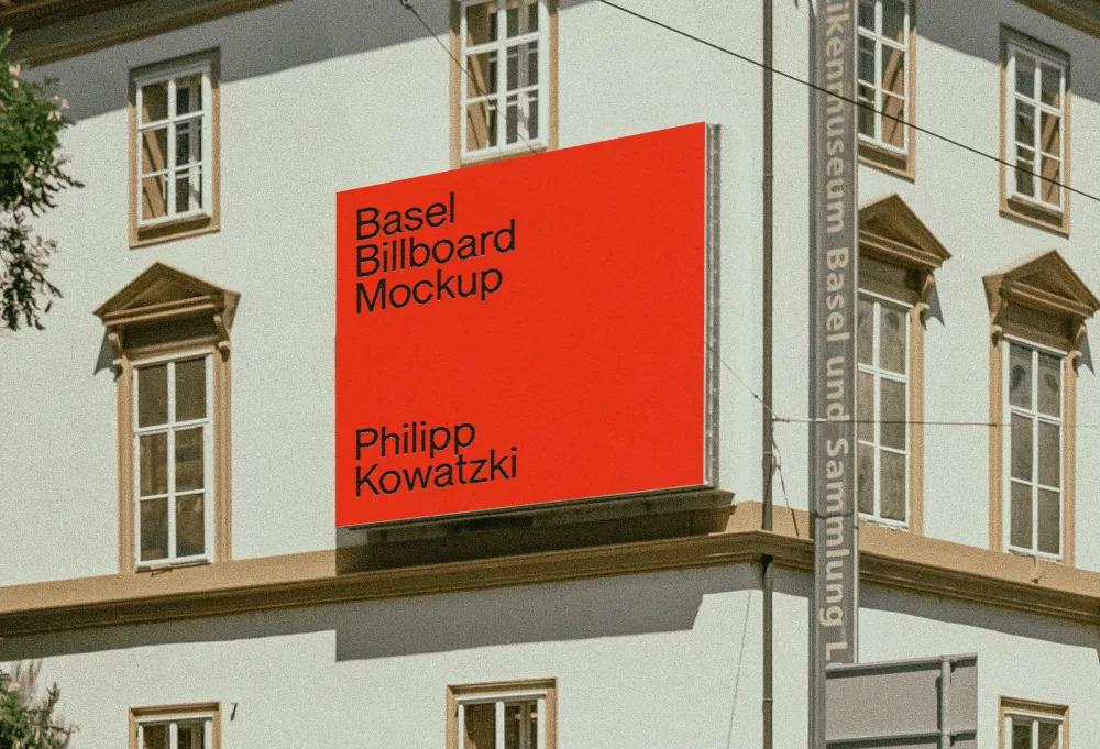 A vibrant red billboard mockup displayed on the side of a classical white building with decorative brown trim and tall windows. A nearby museum banner pole adds an urban cultural context.