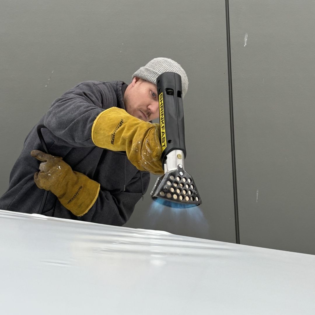 A man doing a shrink wrap of a boat in kelowna BC