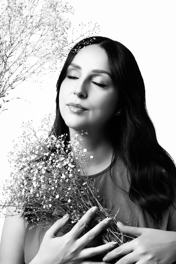 mujer en retrato femenino minimalista en estudio de fotografía con flores delicadas
