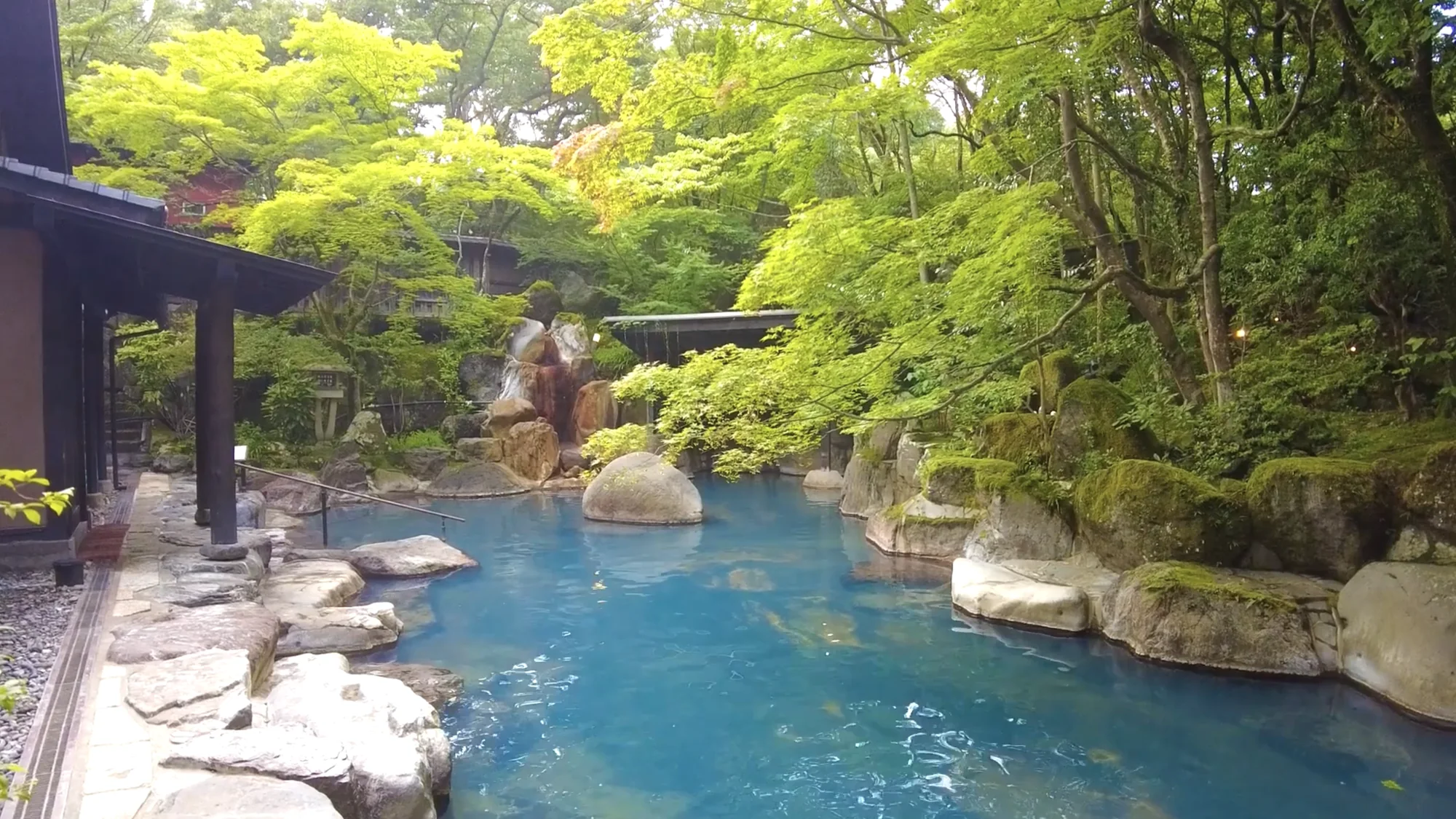 A wide open-air bath among boulders and trees at a Kurokawa inn