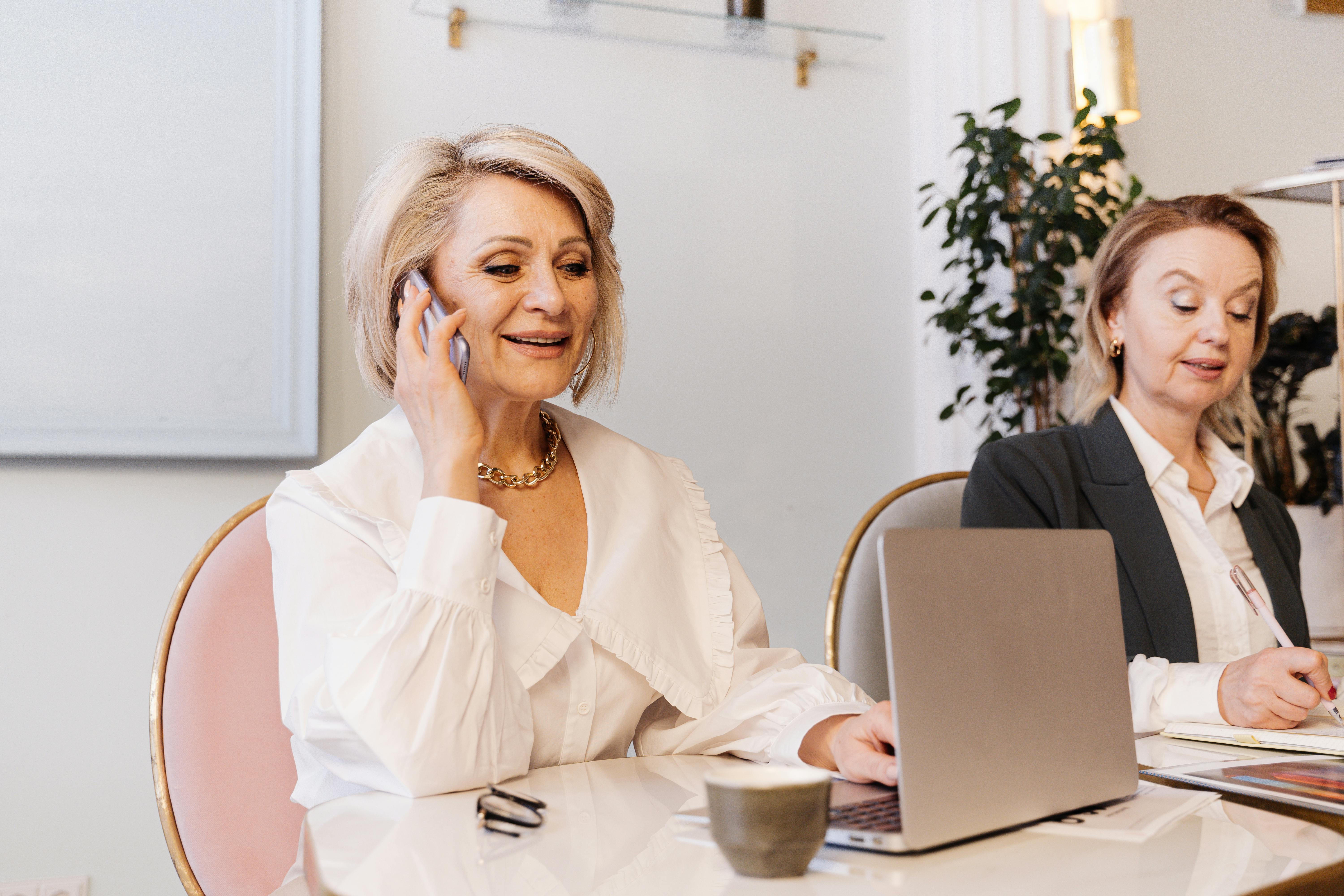 Professional women working in a modern office, using laptop and phone during a business meeting – Sparkyheads recruitment and staffing specialists