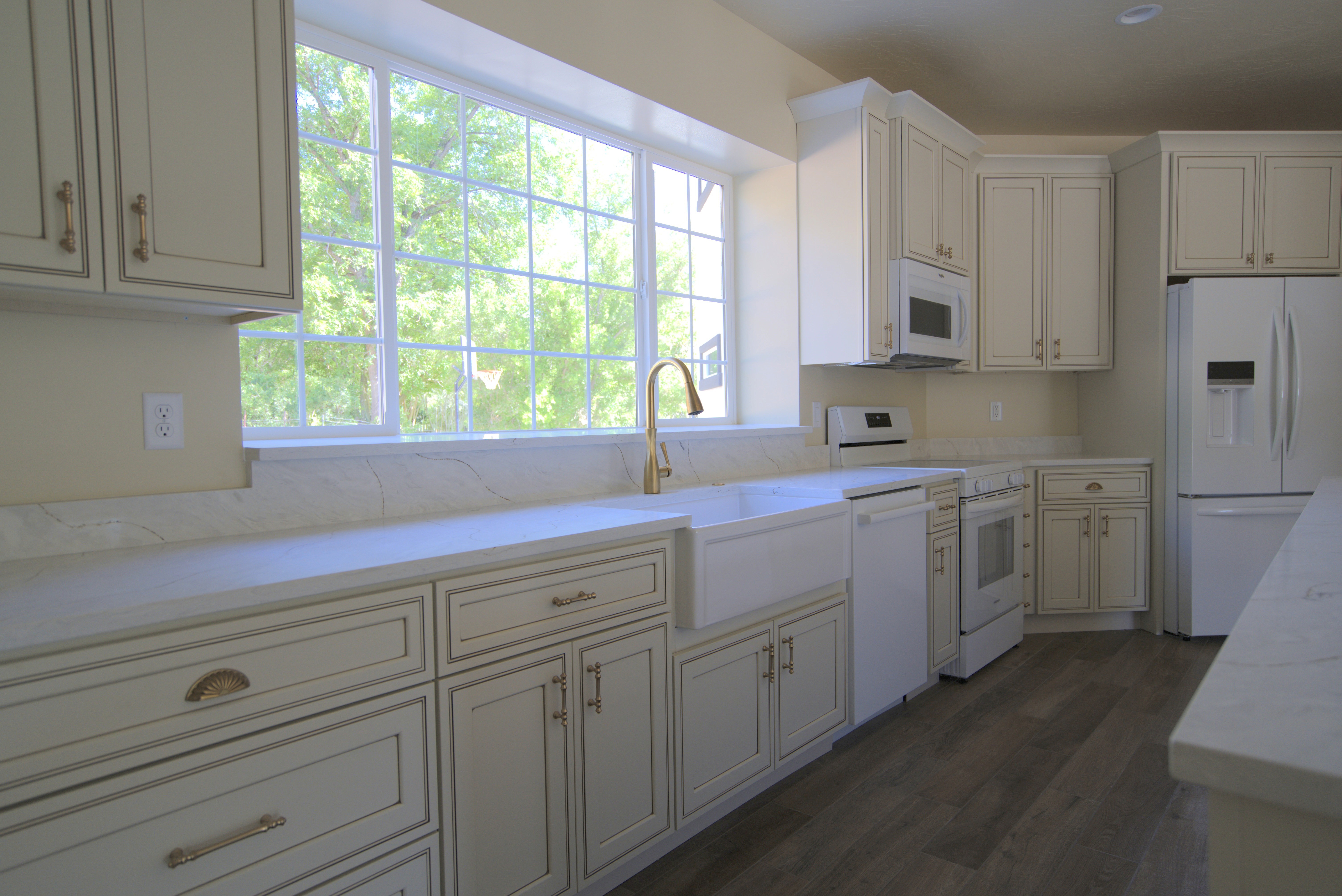 Kitchen in a Southern Utah home with white cabinets, large window with a sink. and a farmhouse sink.