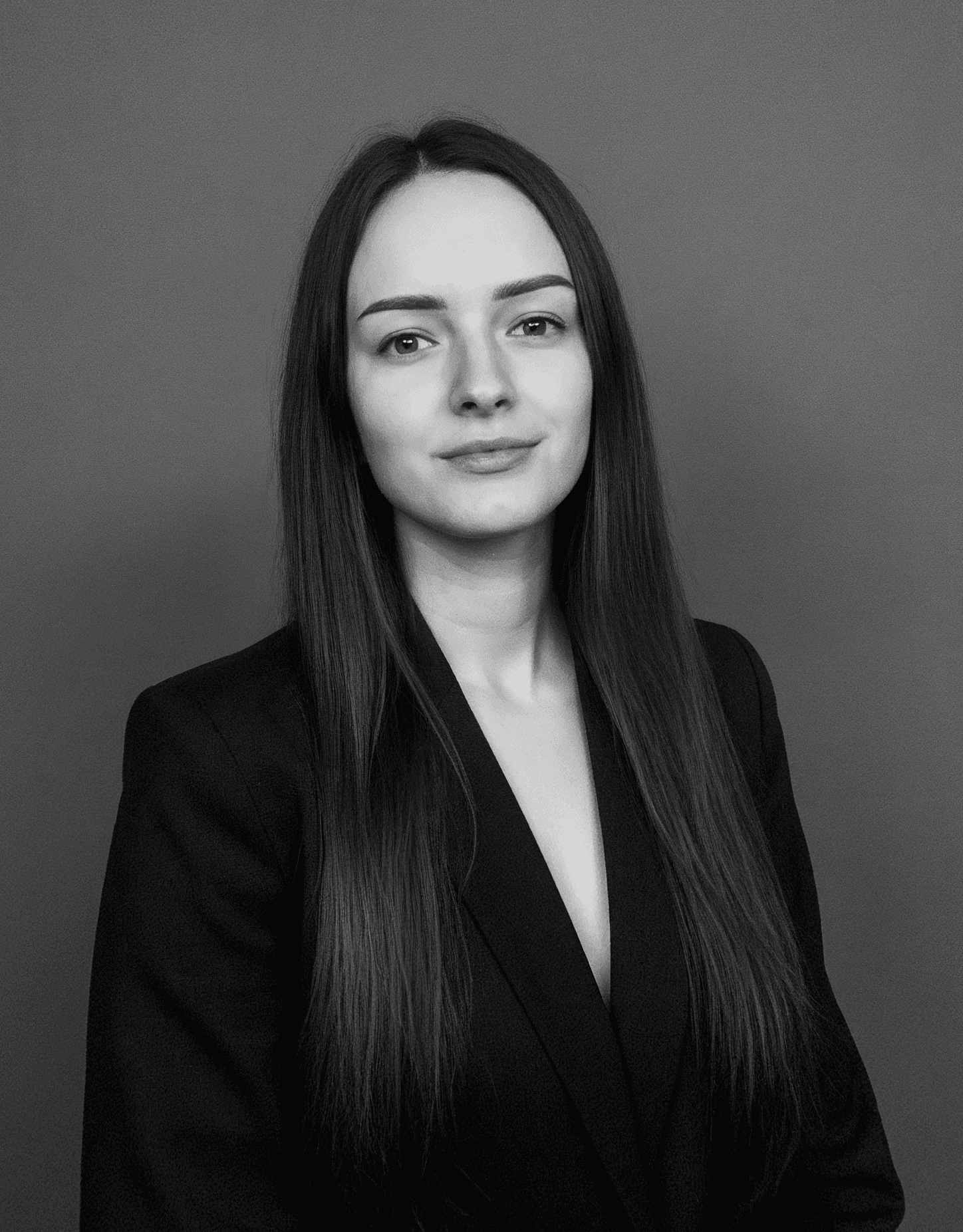 A thoughtful young person with dark hair gazes to the side, captured in soft black and white lighting.