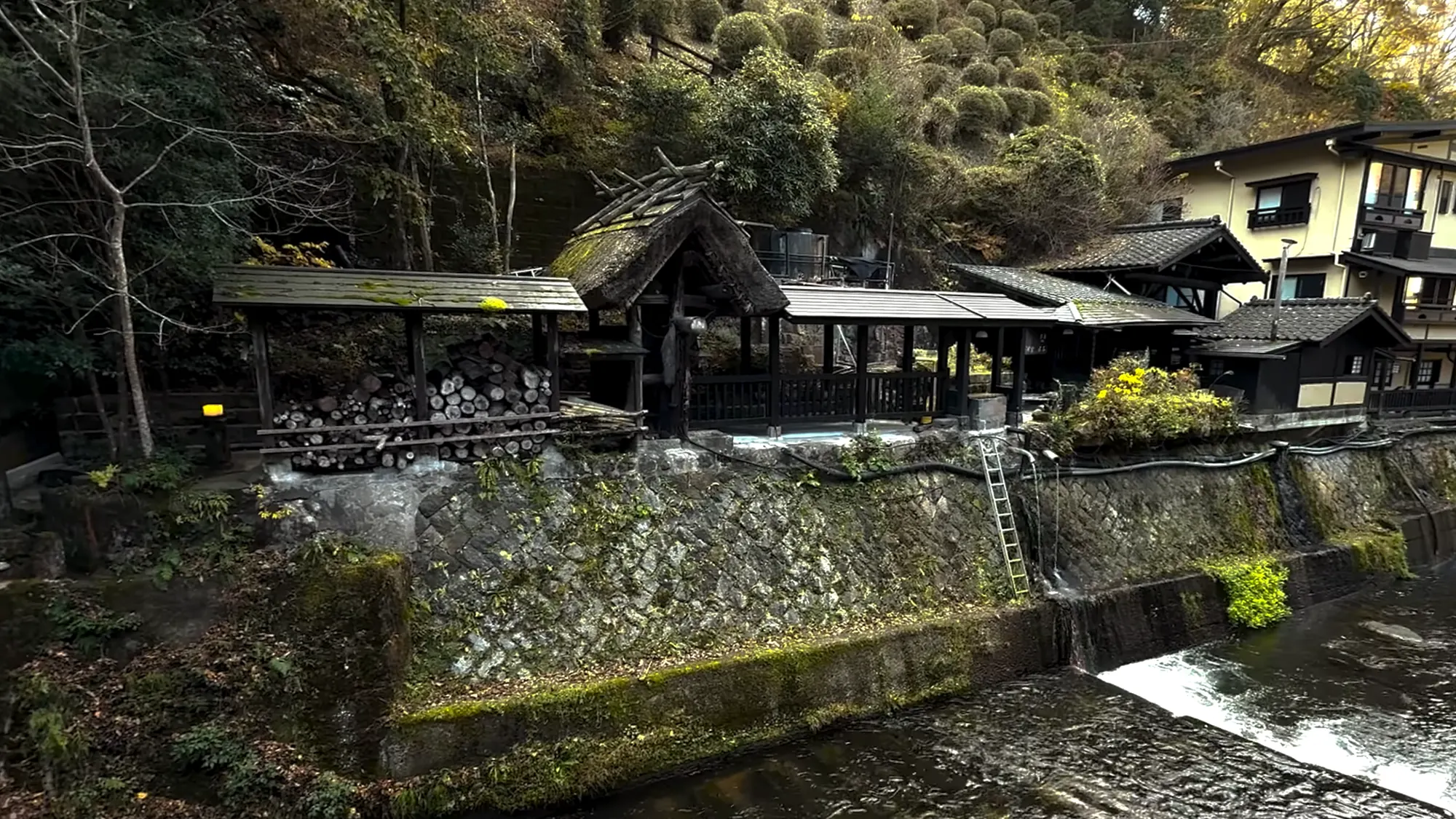 Riverside inn buildings lit above the water at night in Kurokawa