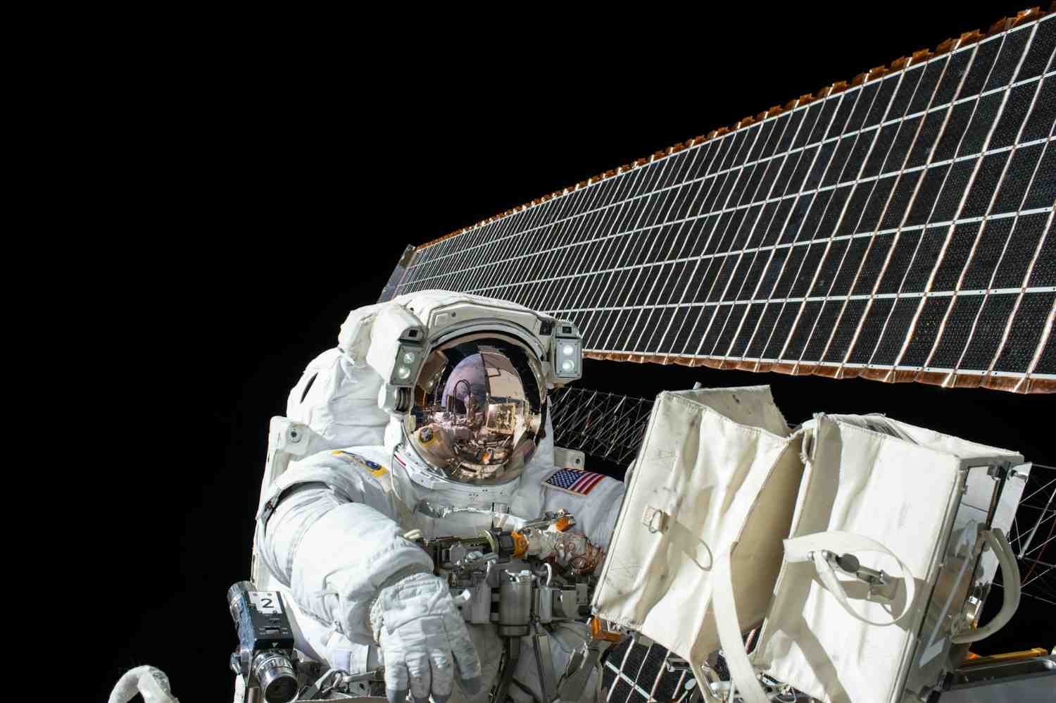 Astronaut performing maintenance near a large solar panel in space