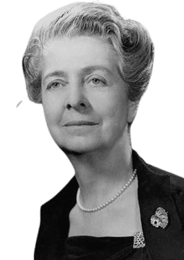 Black and white portrait of an older woman with styled, wavy hair, wearing a pearl necklace and a dark dress adorned with a decorative brooch. She has a composed and gentle expression, exuding elegance and dignity. The soft lighting highlights her poised demeanor and refined appearance.