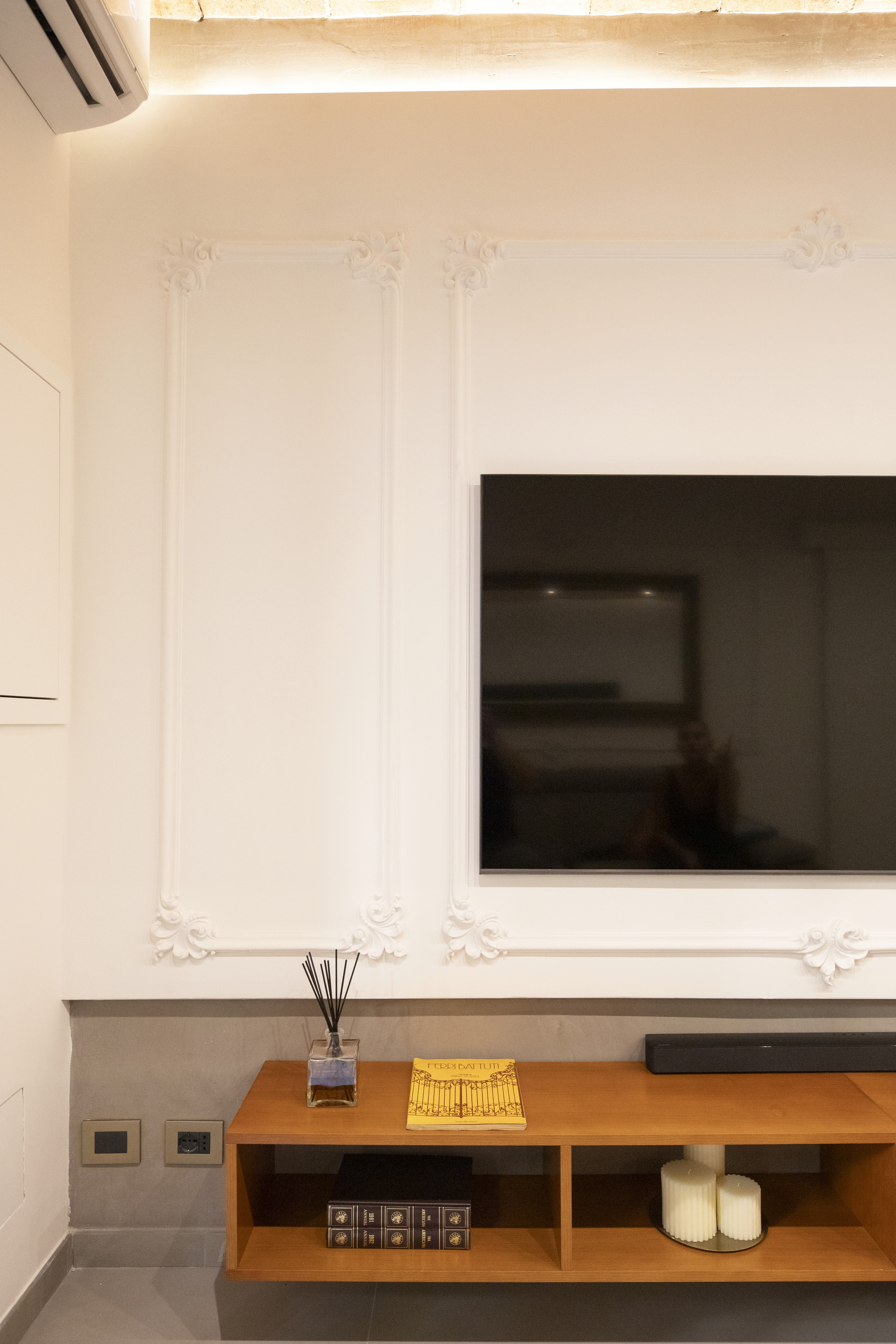 A hotel luggage carrier placed against the wall with a large decorative vase in front of it.