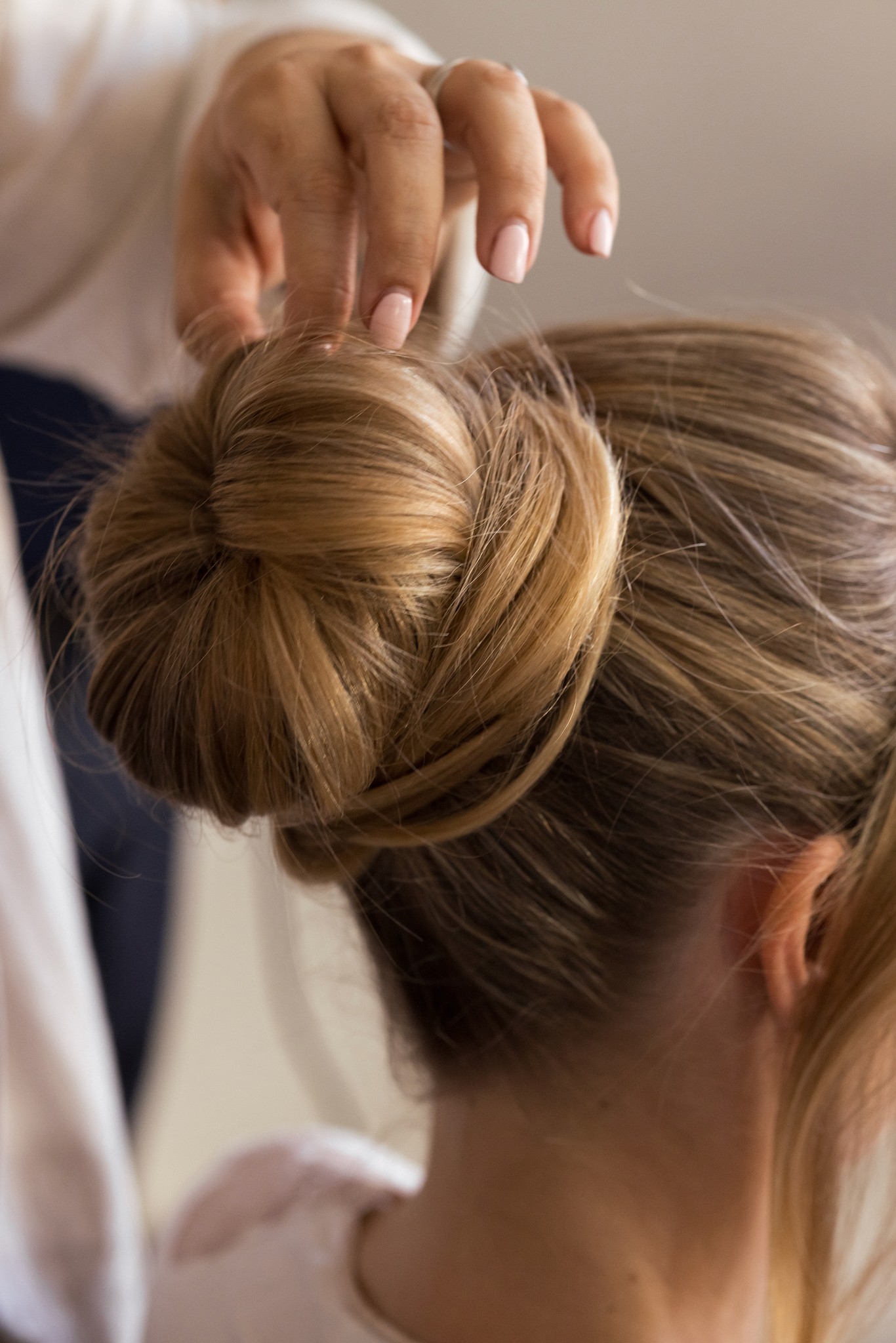 Mani della sposa che sistemano l'acconciatura con chignon durante i preparativi del matrimonio a Villa Malenchini