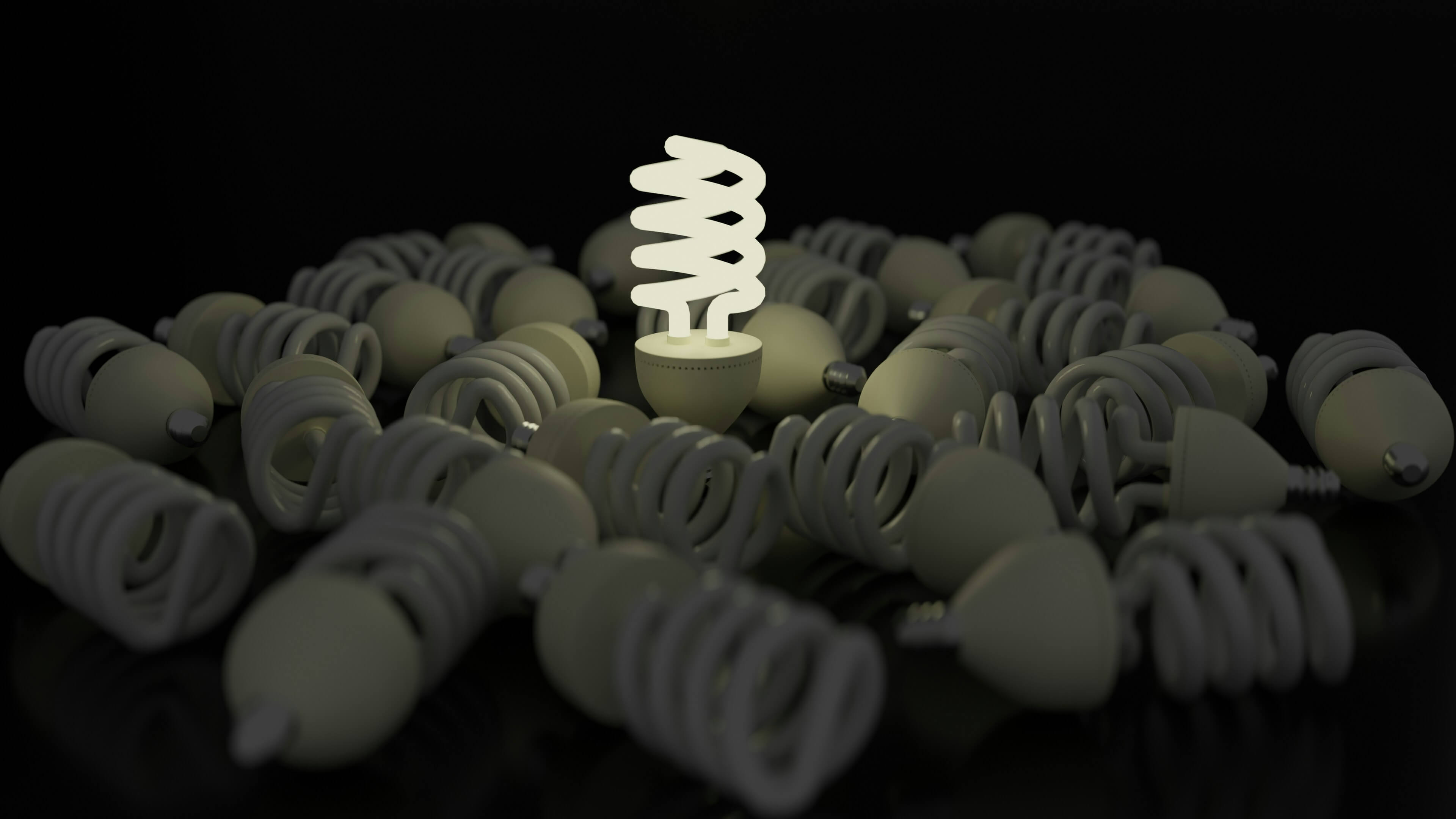 Glowing energy-efficient light bulb surrounded by unlit bulbs representing smarter energy use and electricity savings.