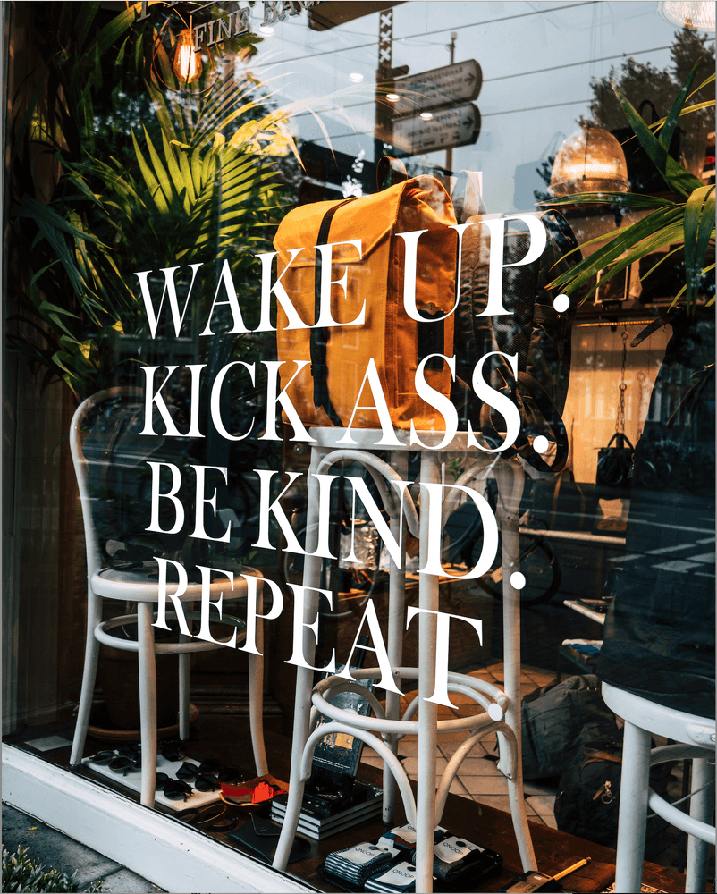 Store front with text on window that says, "Wake up. Kick Ass. Be Kind. Repeat." Credit: Chris Curry - Unsplash