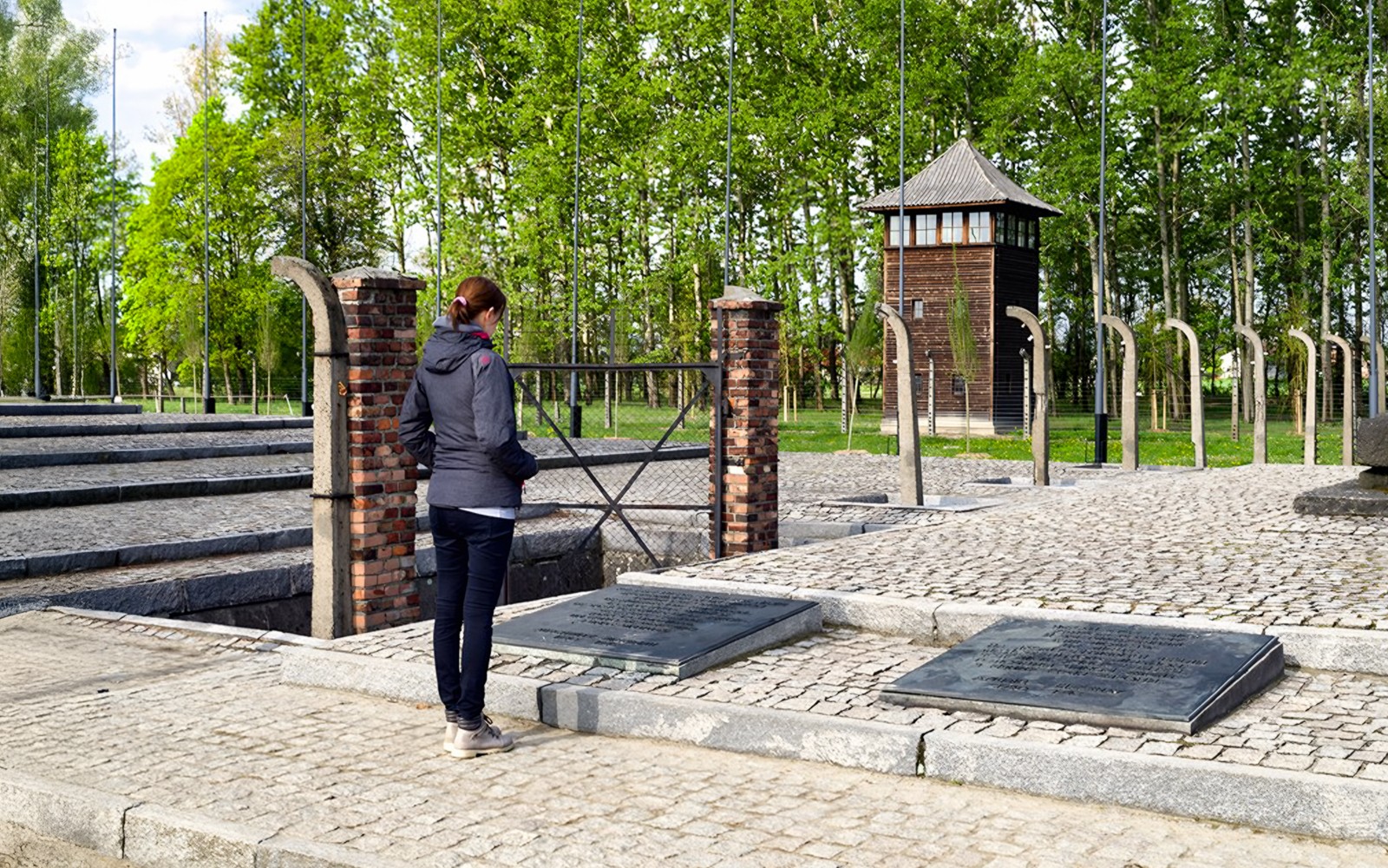 Besökare vid Auschwitz Birkenau minnesplats nära vakttornet och plaketterna.