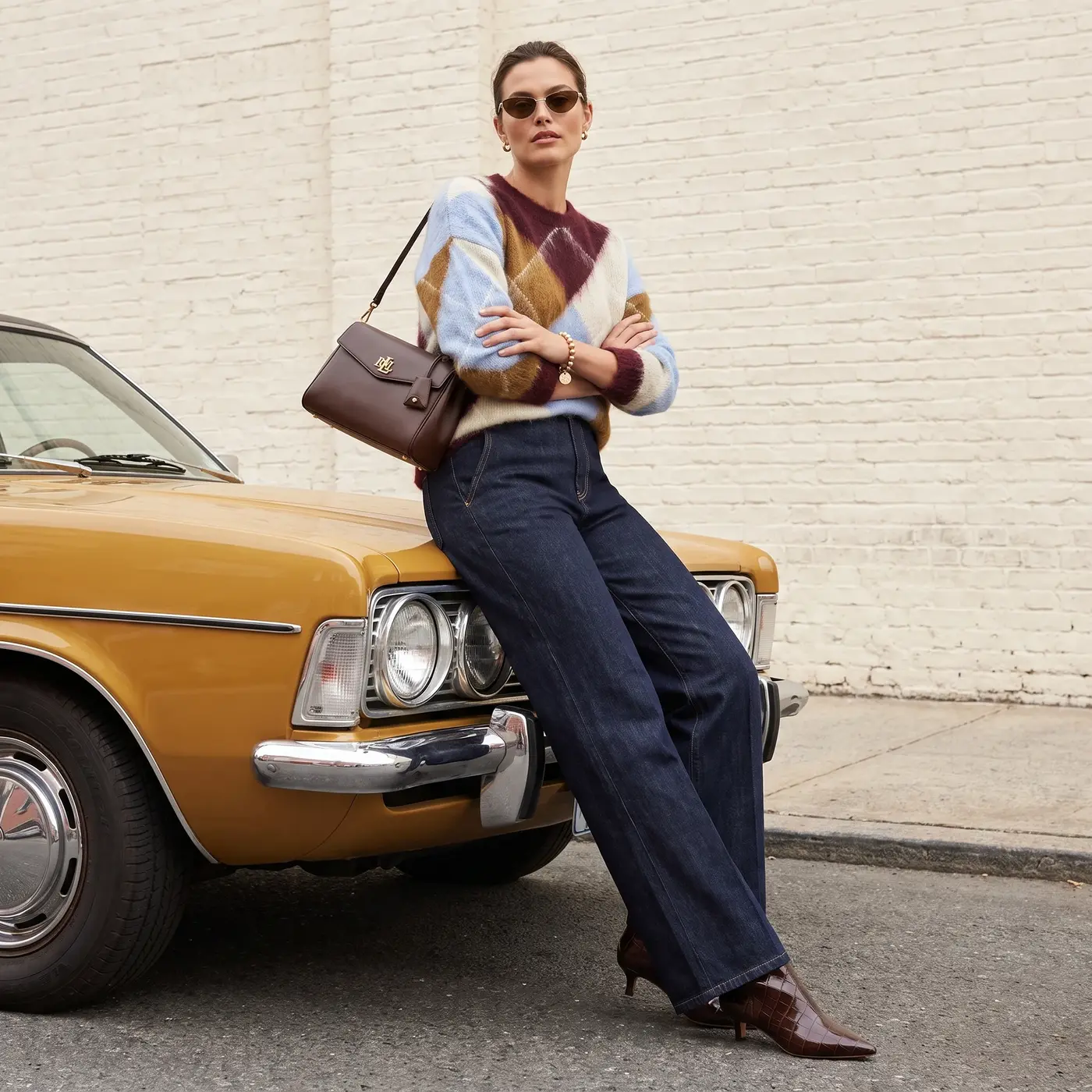 Modella con maglione argyle appoggiata a un’auto d’epoca