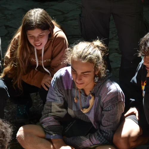 Educatore con ragazzi in cerchio durante attività di consapevolezza in un campo estivo in natura in Toscana