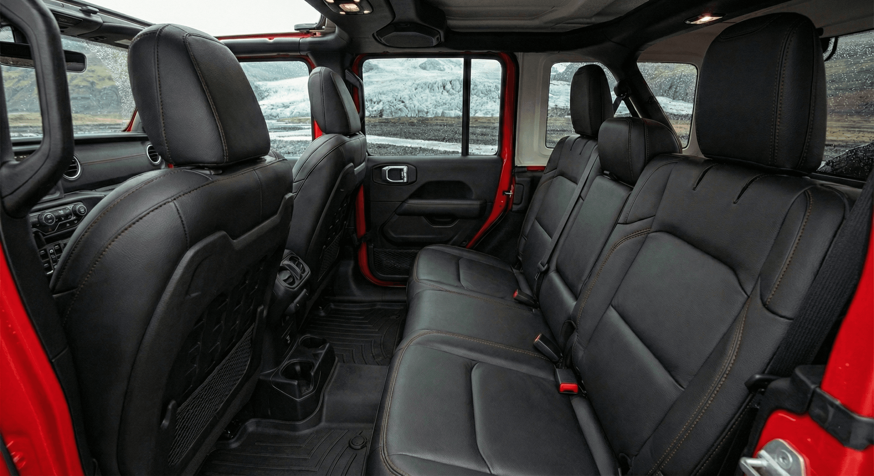 Interior view of the rear seats of a vehicle featuring black leather with red stitching.