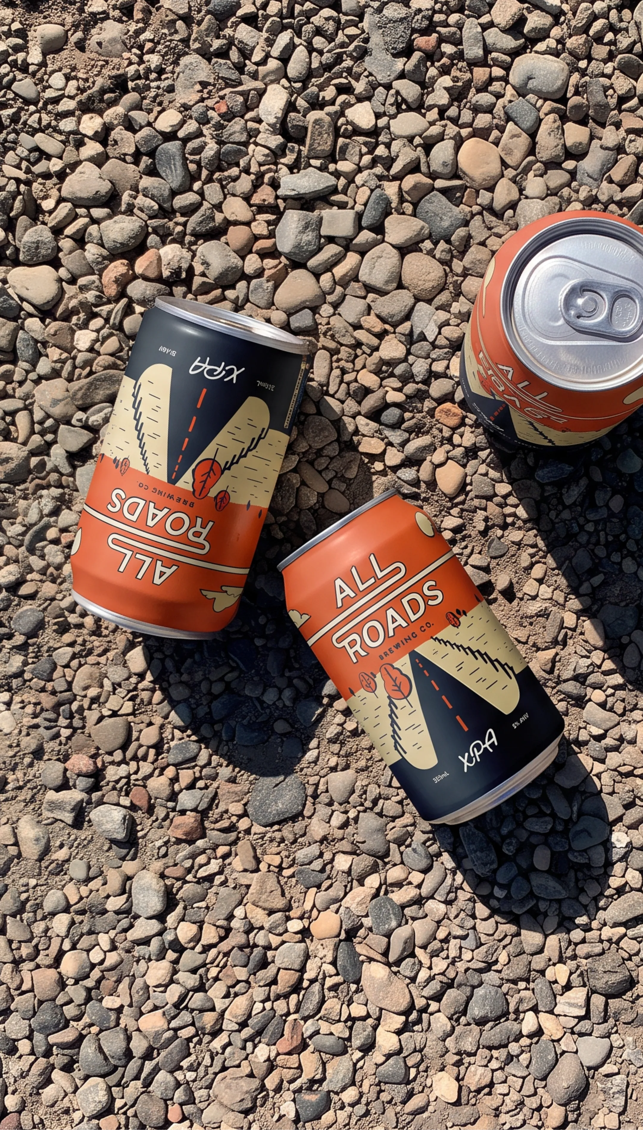 All Roads Brewing Co. brand photography showing 3 XPA cans on dirt ground