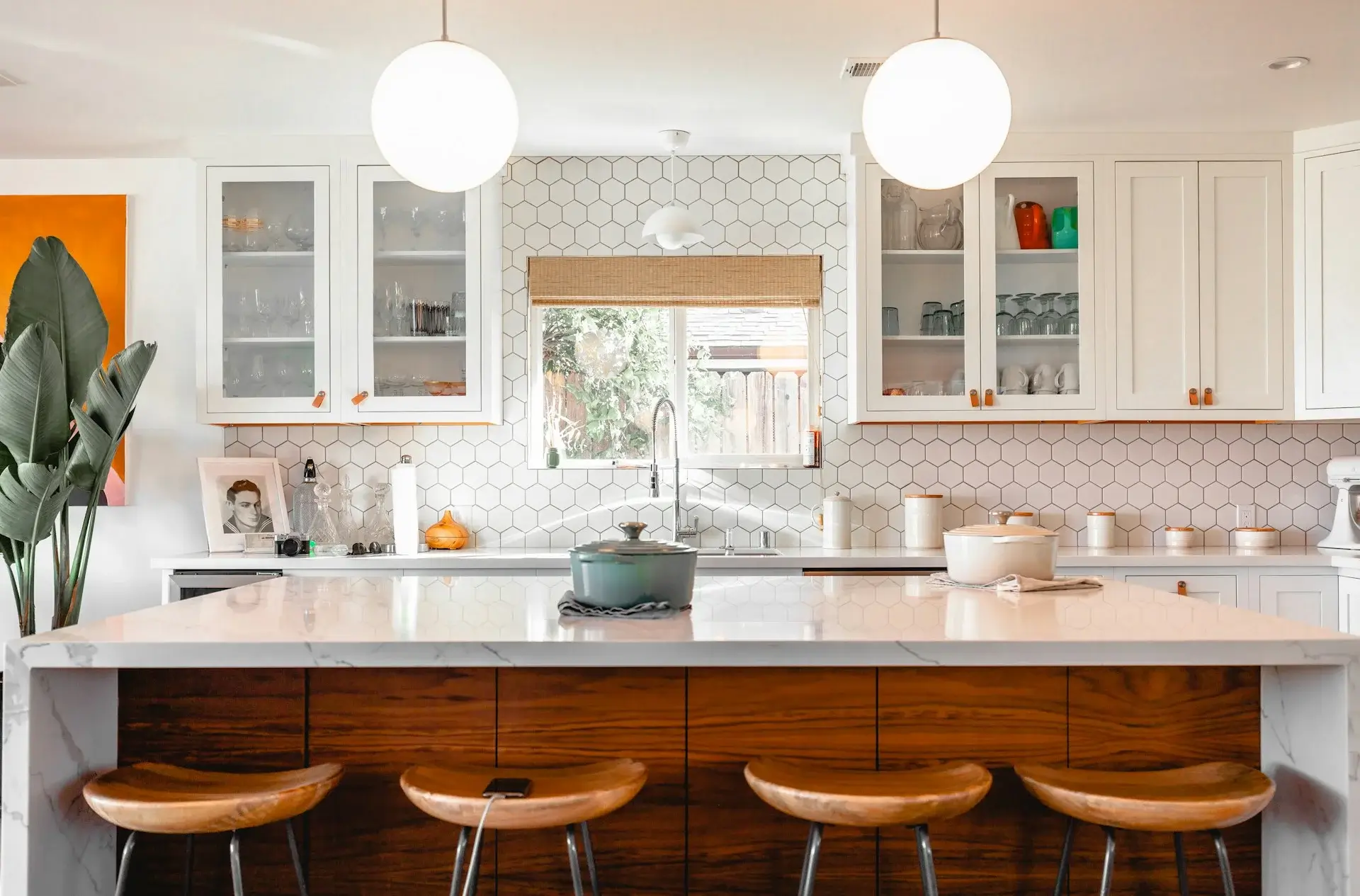 Modern white kitchen with hex tile backsplash, large island, and bar stools.