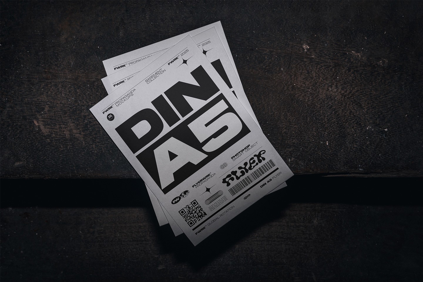 Stack of A5 flyers lying on a dark, weathered concrete floor in a basement setting