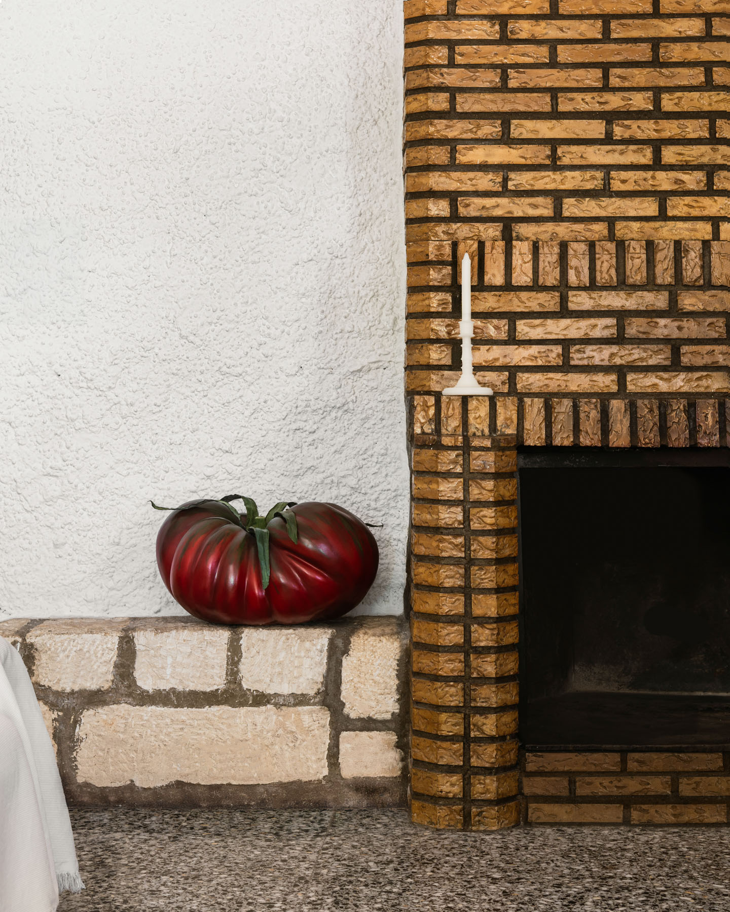 Giant tomato displayed beside a rustic fireplace evoking the Spanish summer.