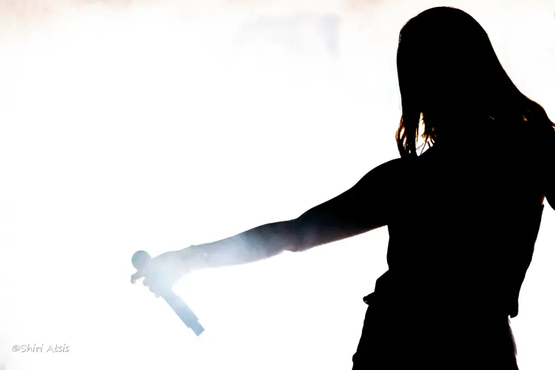 צילום צללית אומנותי של מארינה מקסימיליאן אוחזת מיקרופון על רקע לבן בוהק, מאת הצלמת שירי עציץ - Shiriz