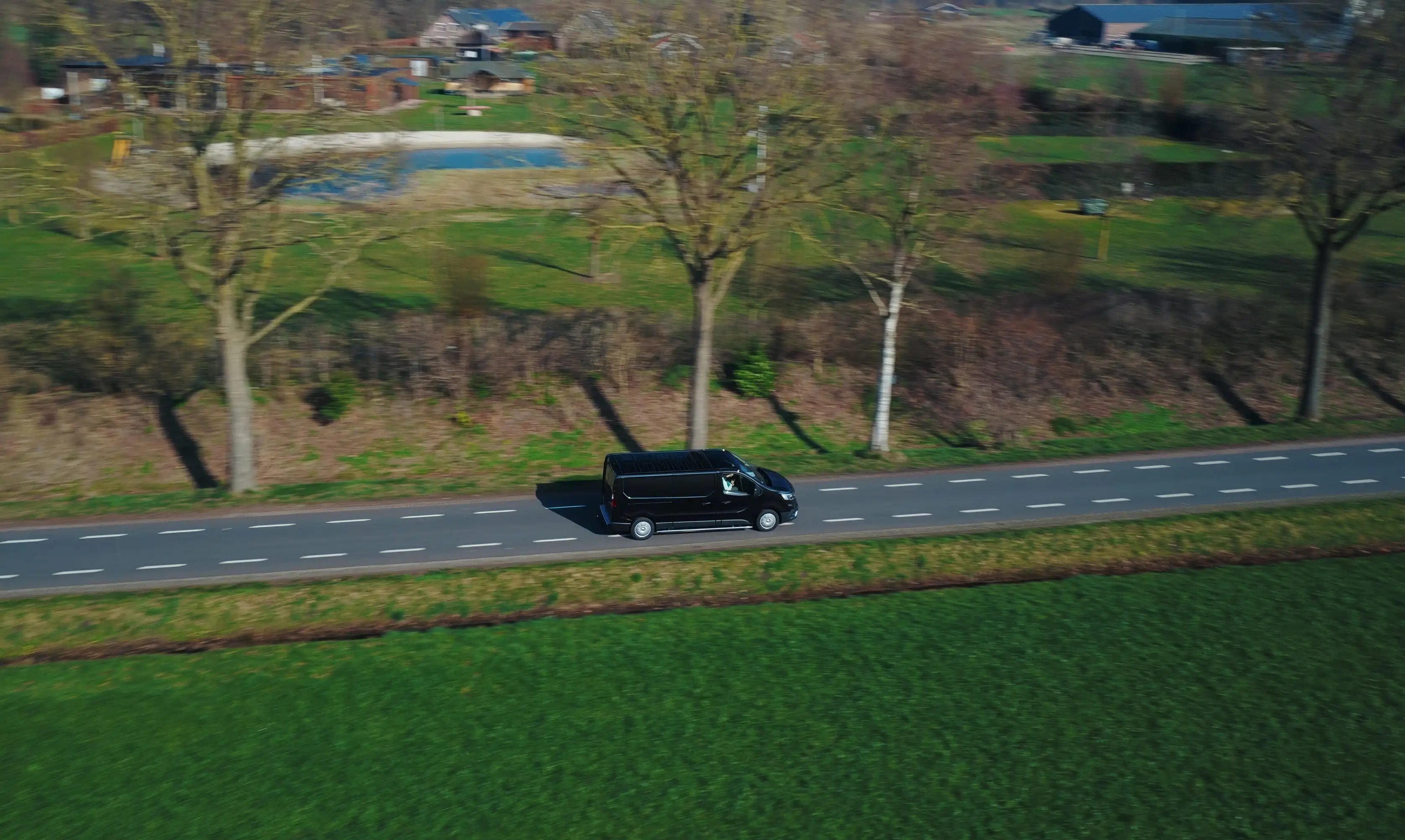 Dronebeeld van een koeriersbus op een landweg