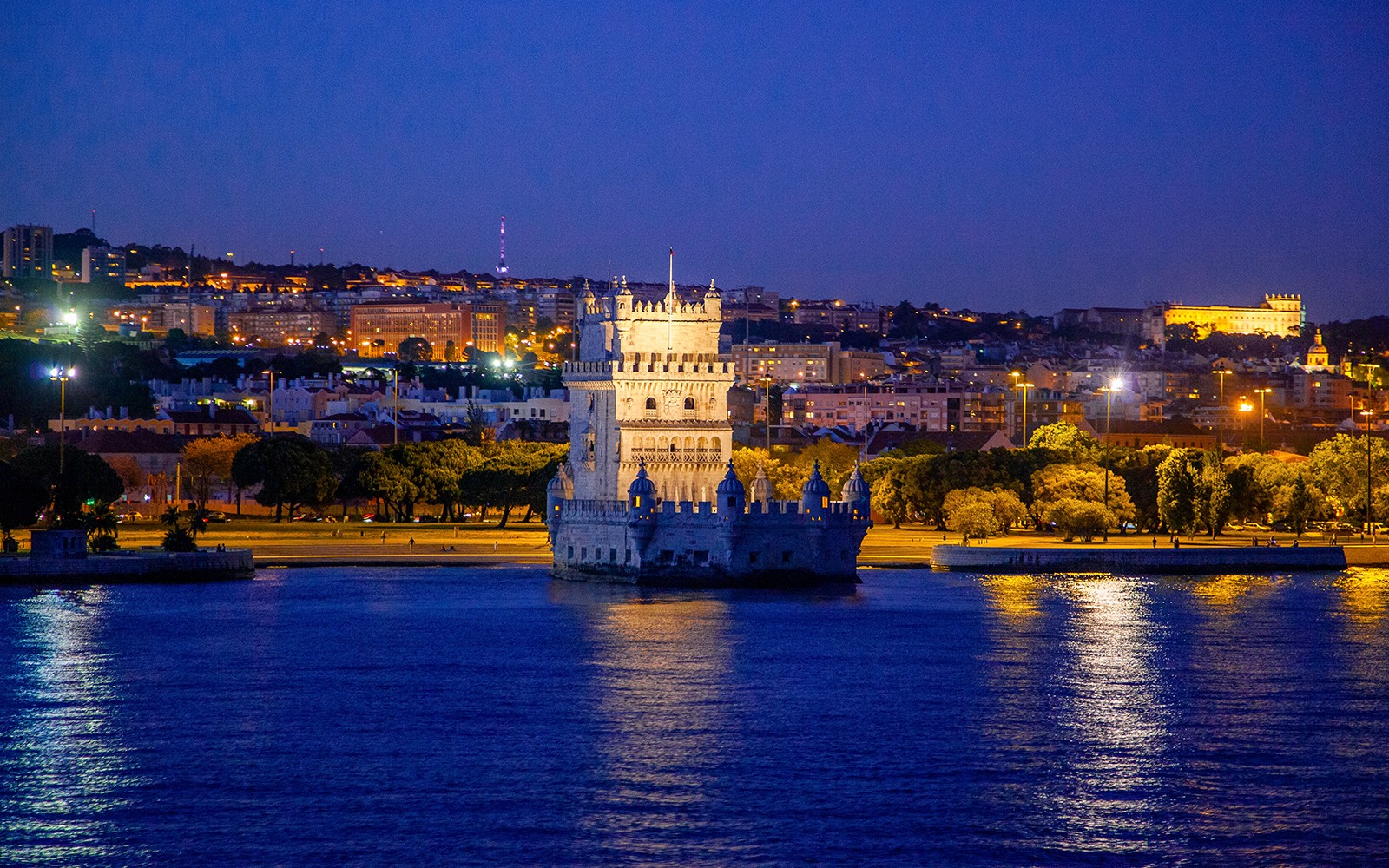 Torre de Belém iluminada à noite durante um cruzeiro em Lisboa.