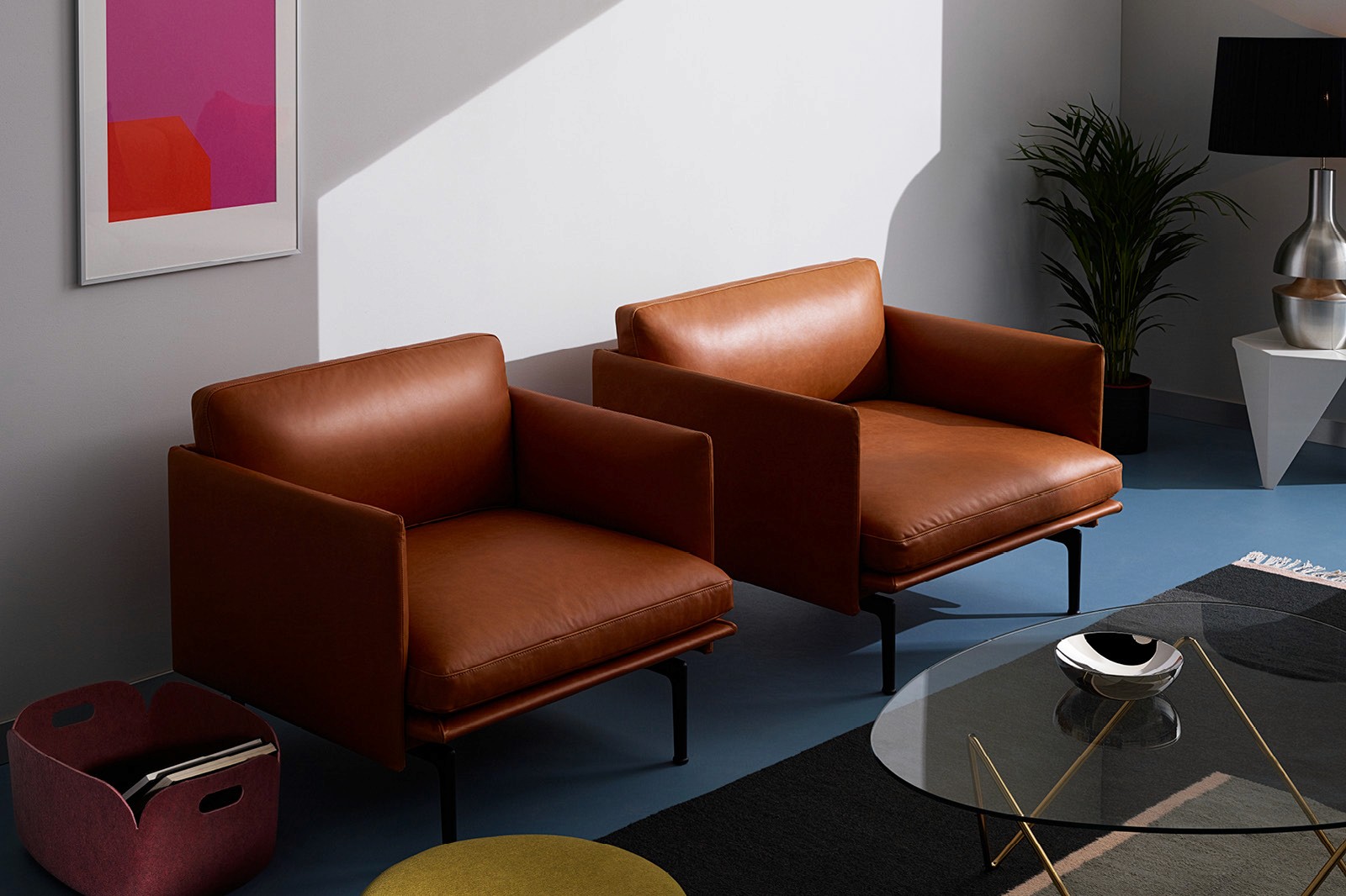 A modern living space featuring two brown leather chairs, a coffee table, and colorful decor in natural light.