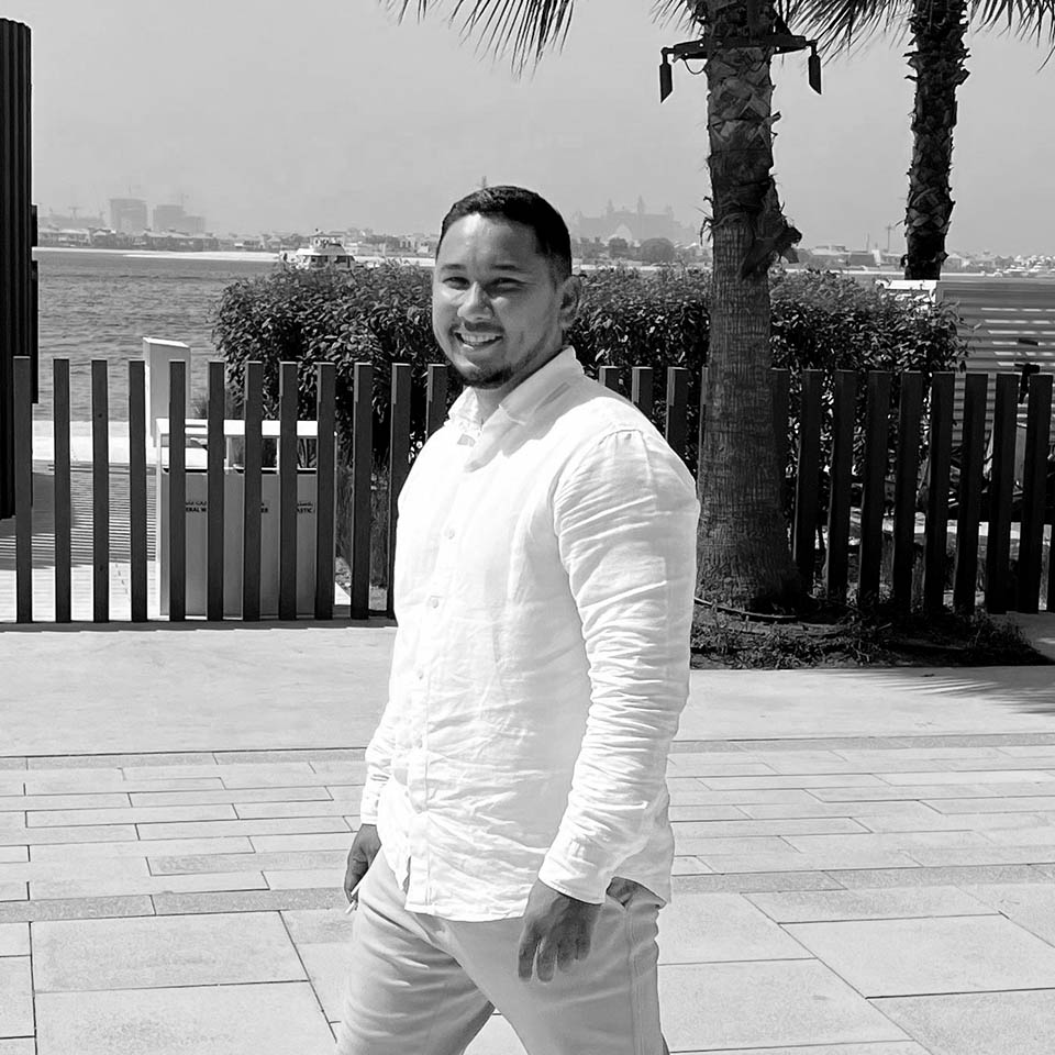 Portrait of a young man with short hair, wearing a dark t-shirt, against a plain background.