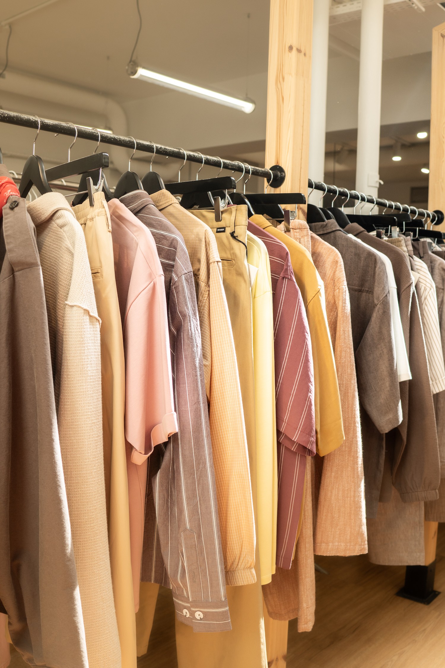 Vu de près, des vêtements jaune, beige, bruns sur un portant
