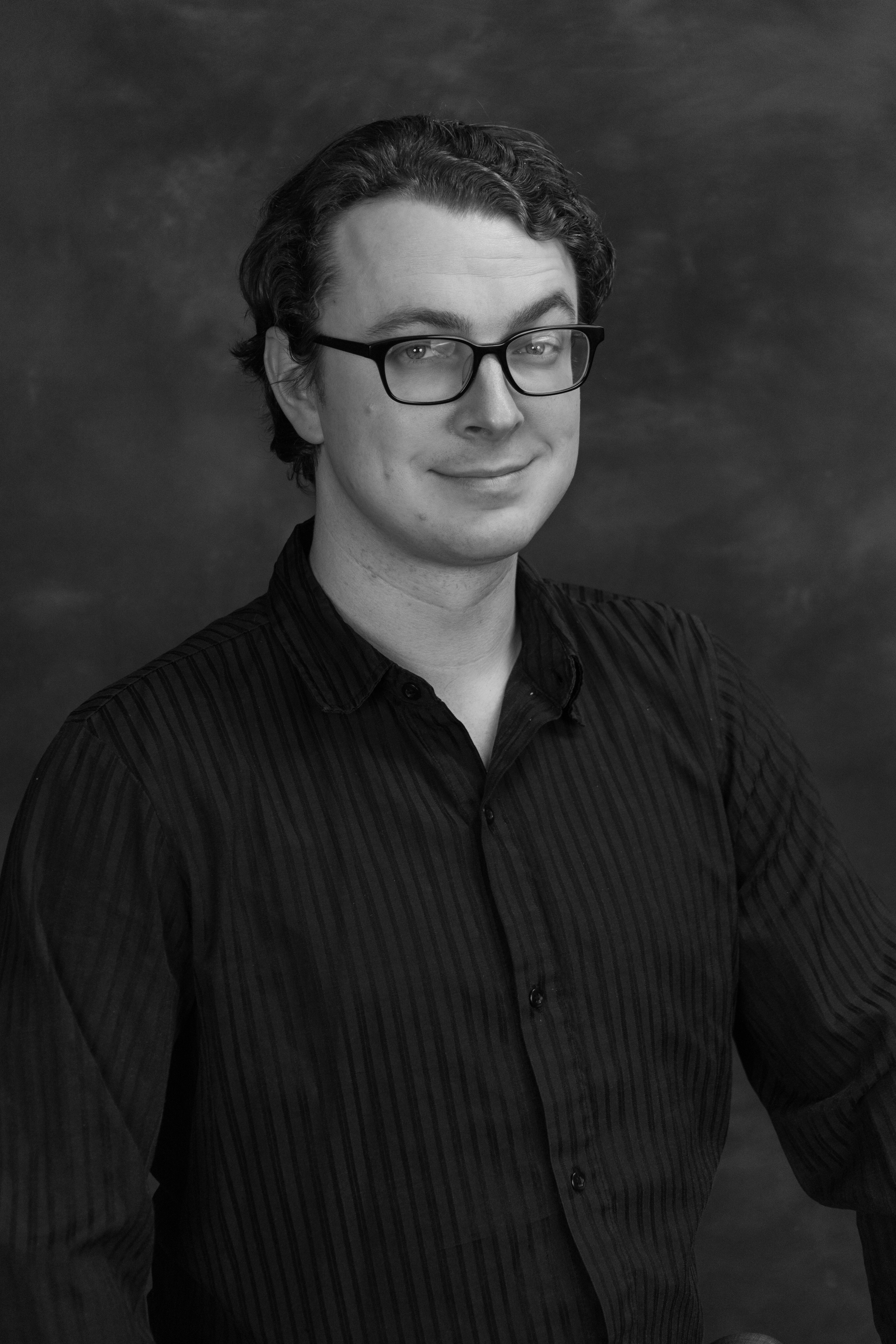 Head shot of an actor, grayscale on a black background.