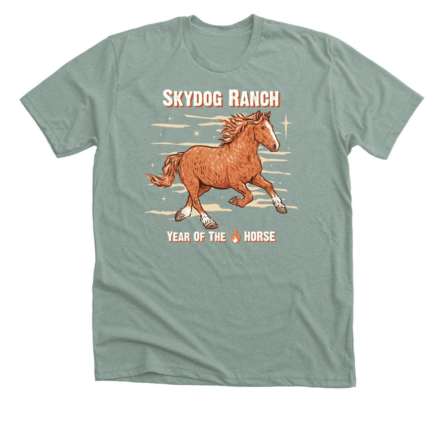 This image features a gray-green t-shirt displaying an illustrated brown horse galloping, with the words "Skydog Ranch Year of the Horse" in stylized text against a starry backdrop.