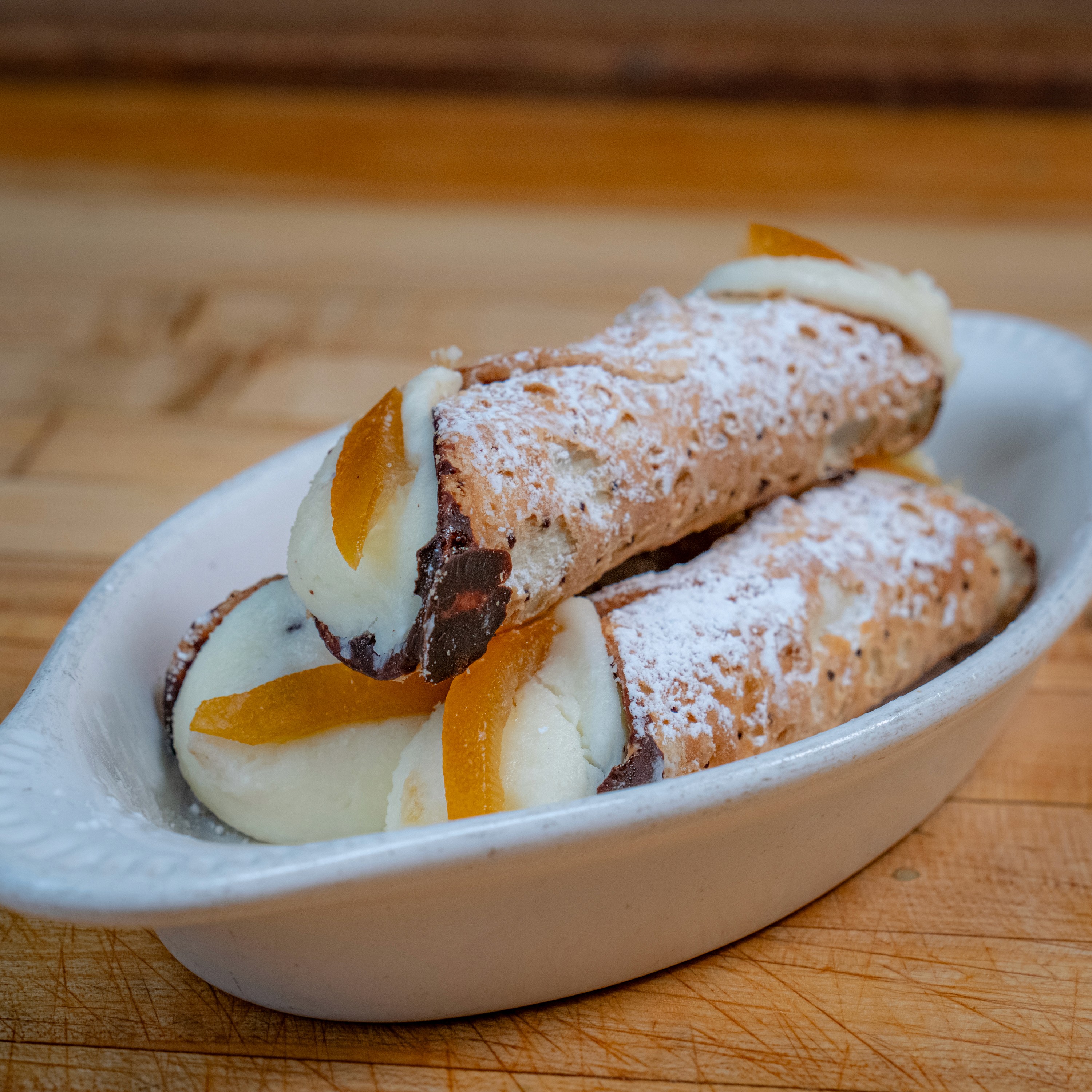 Cannoli dusted with powdered sugar and candied orange