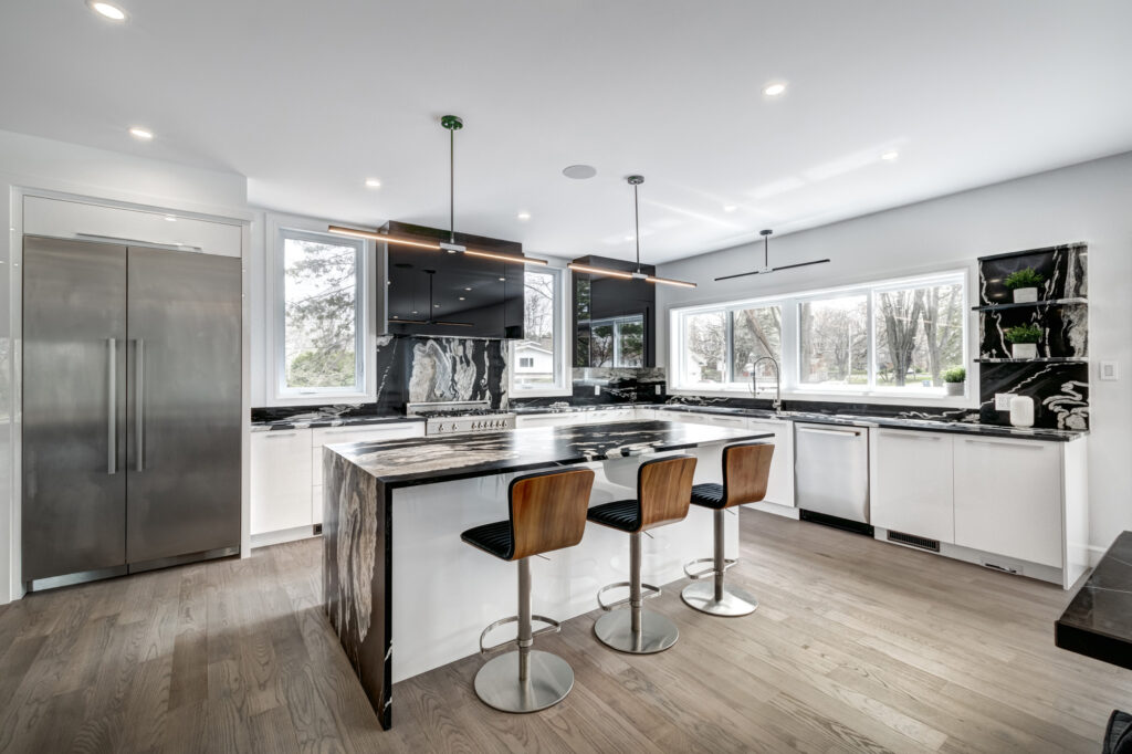 Luxury kitchen renovation with bold black and white marble island and backsplash, sleek black cabinetry, stainless steel appliances, and wraparound windows, showcasing B&Y Reno Corp’s high-contrast modern design