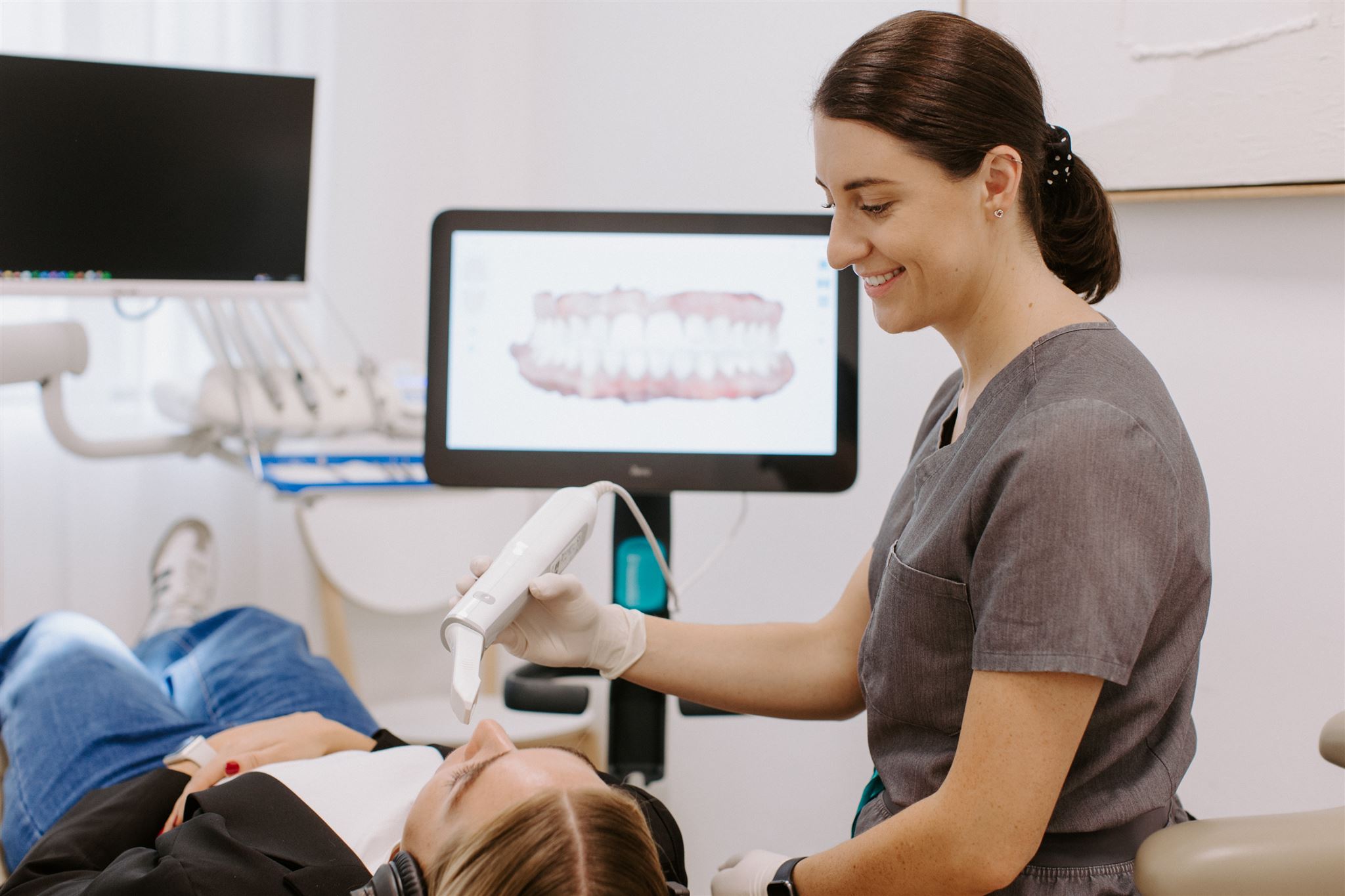 Friendly dental nurse using an ITero scanner for her patient