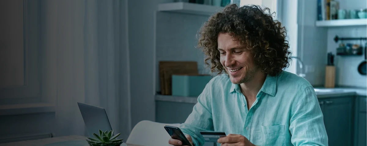 Homem com um celular e um cartão de crédito na mão