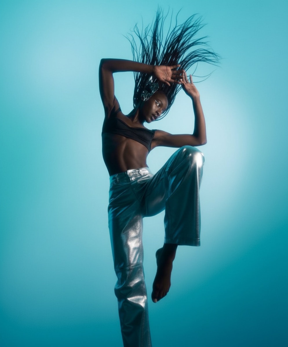A dancer poses dynamically against a teal background, showcasing fluid movement and expressive body language.