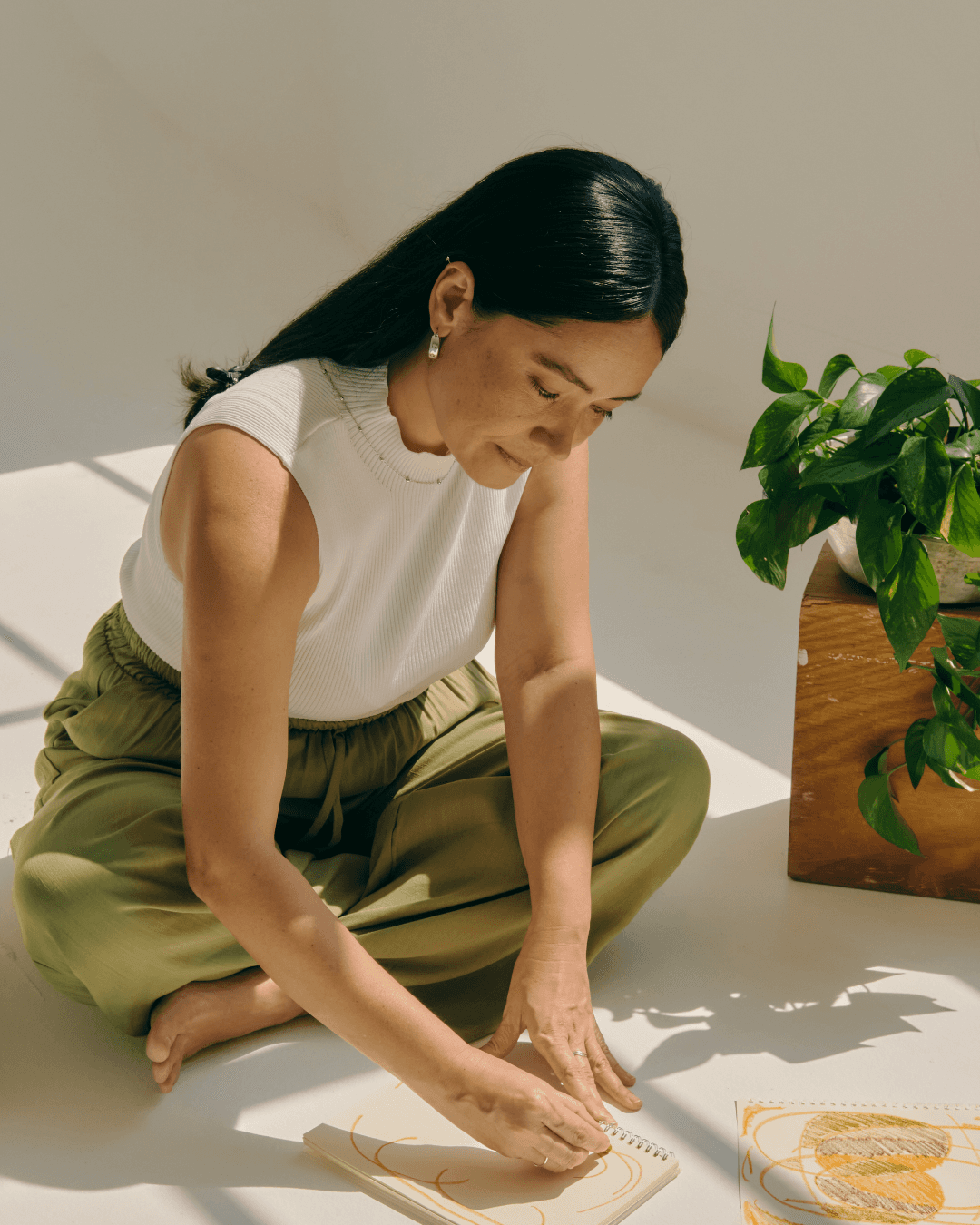 person writing on brown wooden table near white ceramic mug
