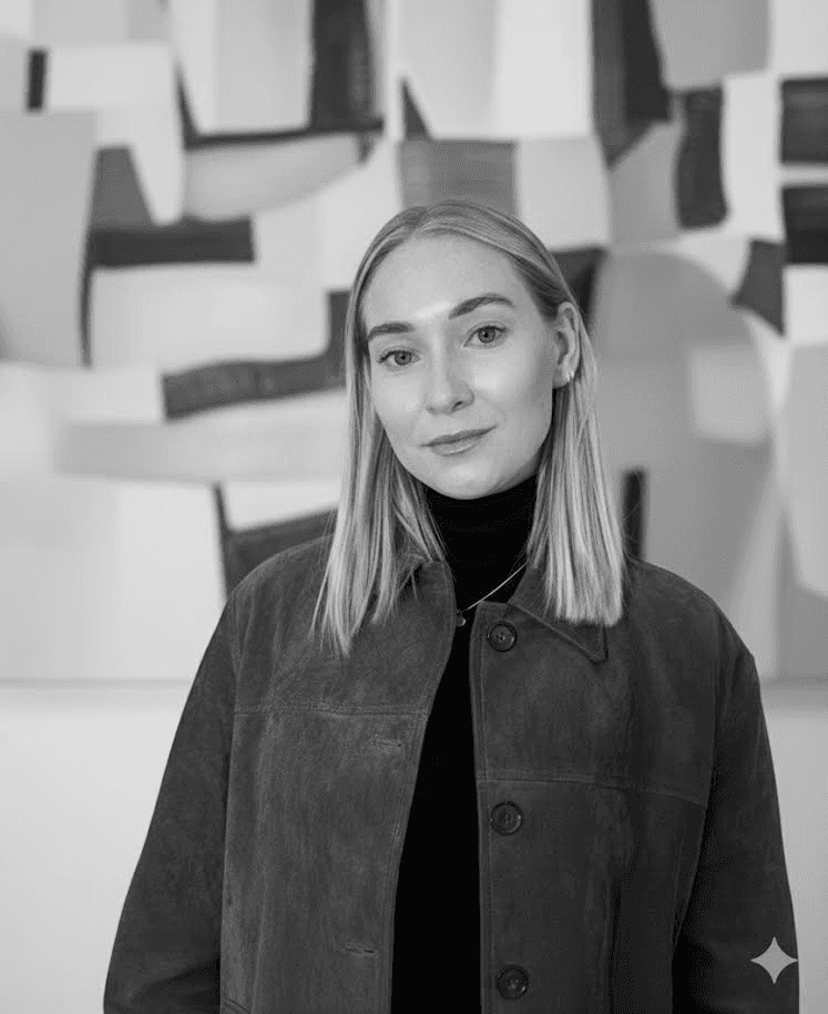A thoughtful young person with dark hair gazes to the side, captured in soft black and white lighting.
