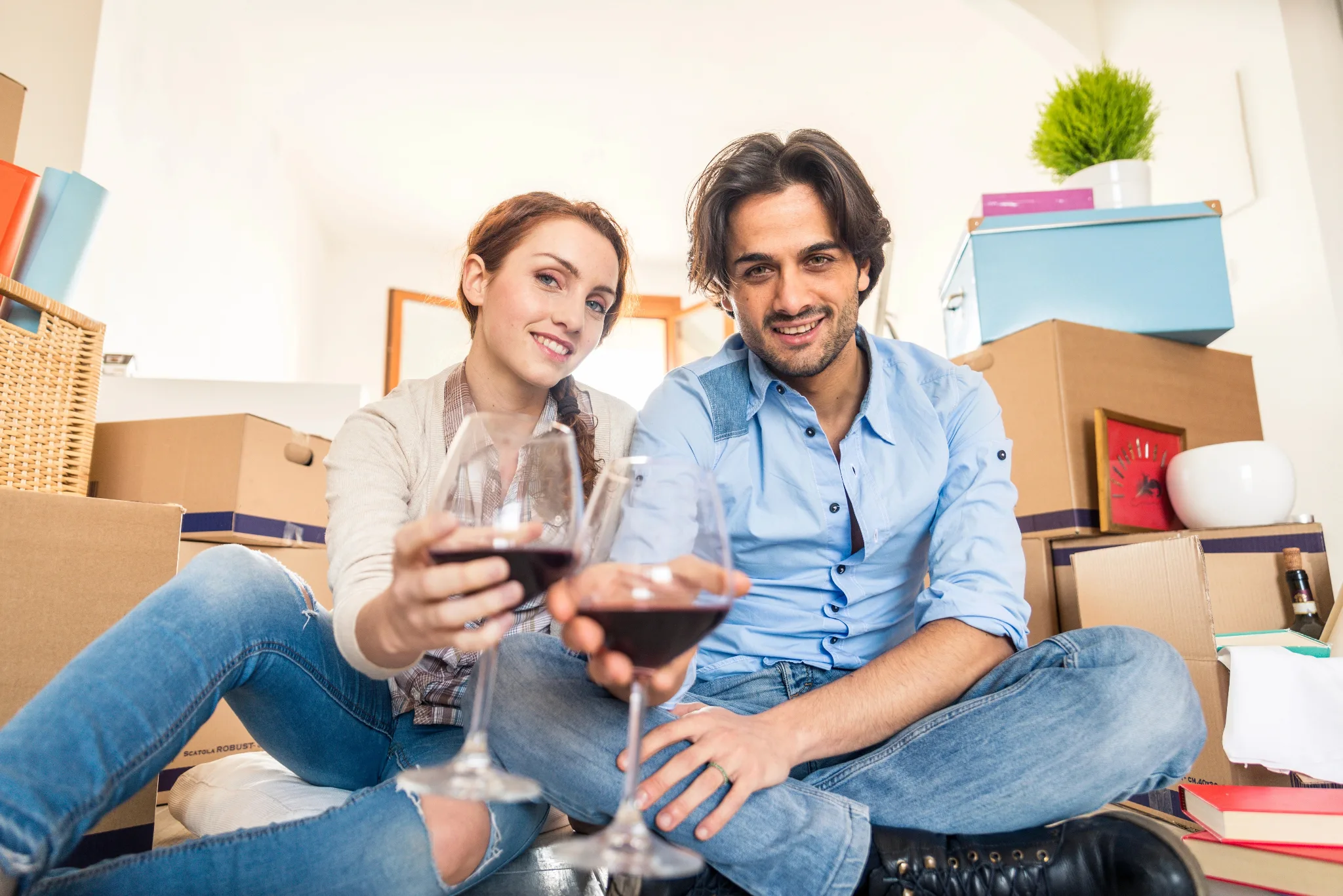 A couple sitting on the floor,  enjoying red wine.