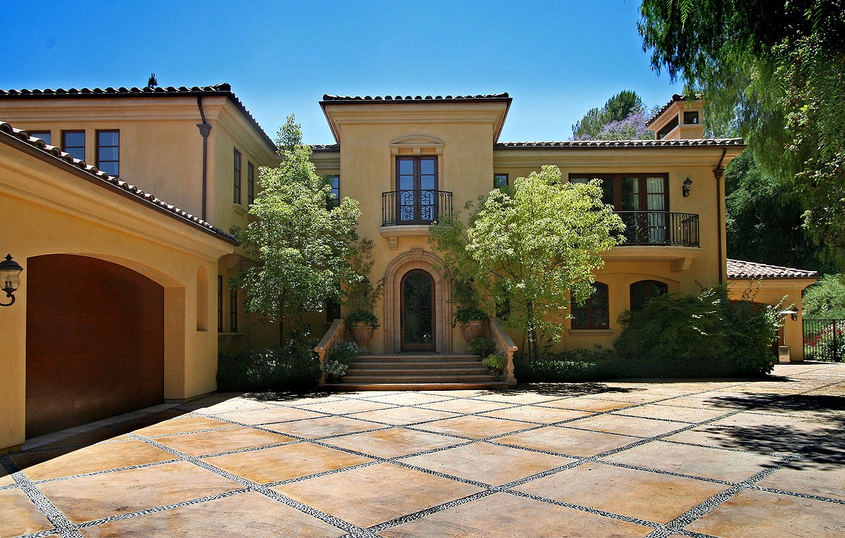 Driveway entry with lush greenery, emphasizing the villa's grandeur and inviting entrance.