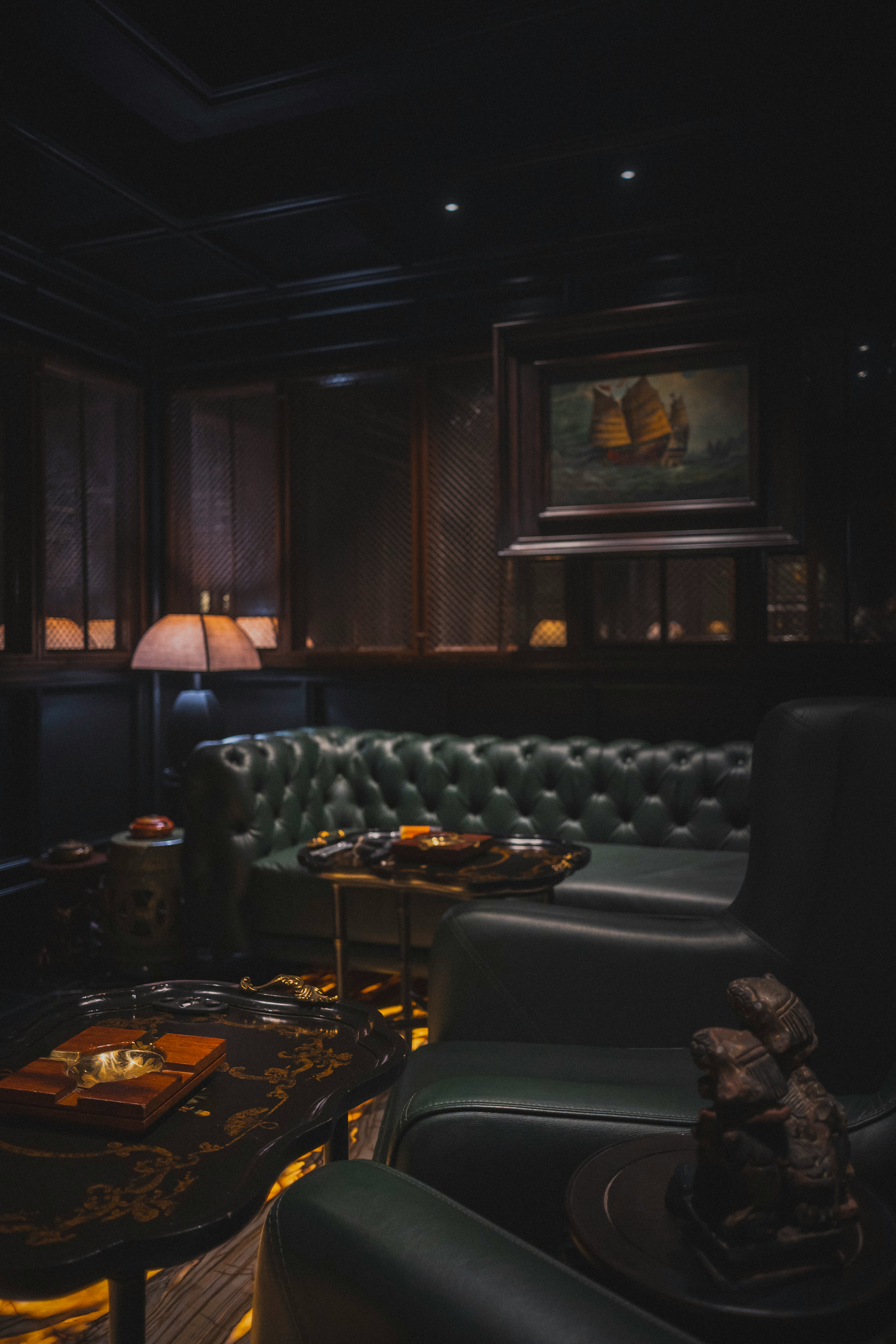 Luxurious dark room with green leather chesterfield sofa.
