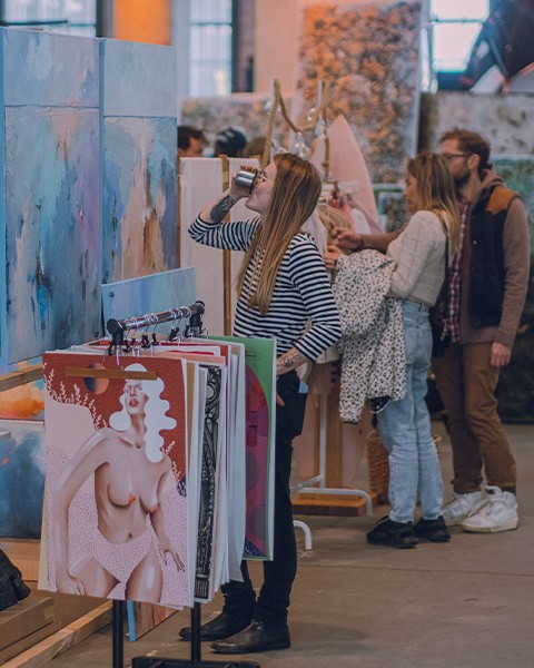 Zdjęcie przedstawiające grupę ludzi, którzy oglądają obrazy.