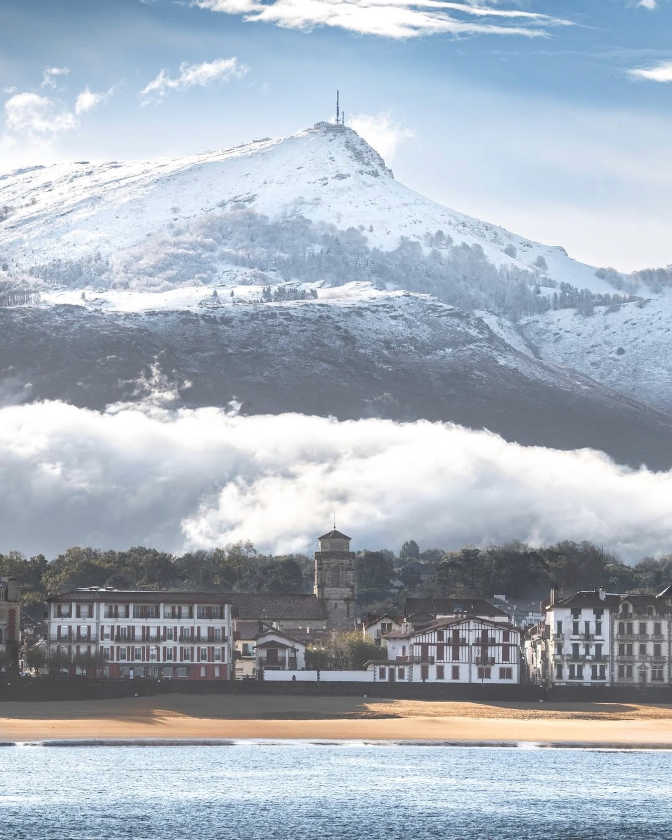 Scenic view of the rugged Basque cliffs and local surfers riding waves at Parlementia break in Guéthary during a guided coastal tour.