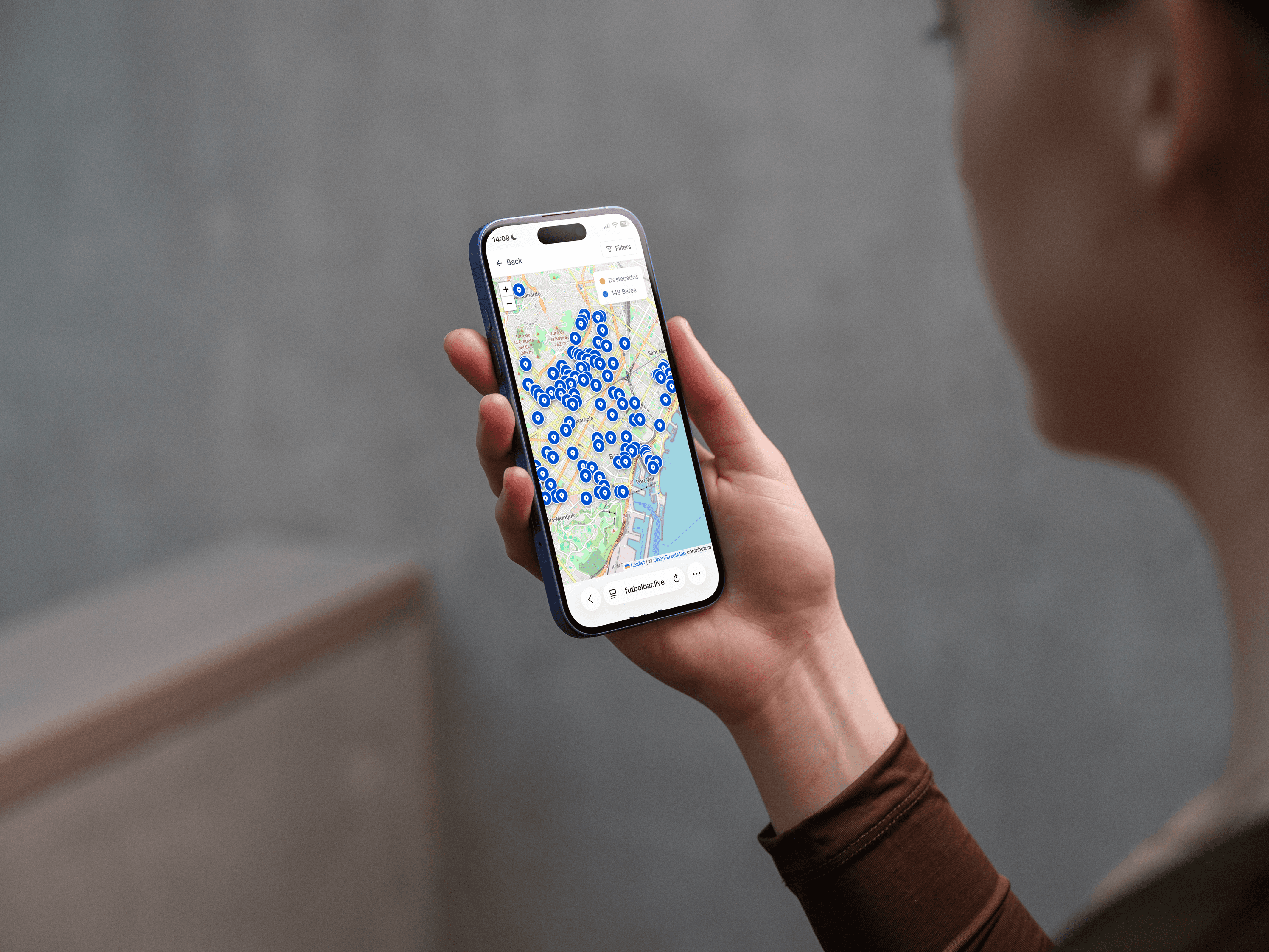 Person holding a smartphone showing the FutbolBar map interface for finding nearby bars streaming live football matches