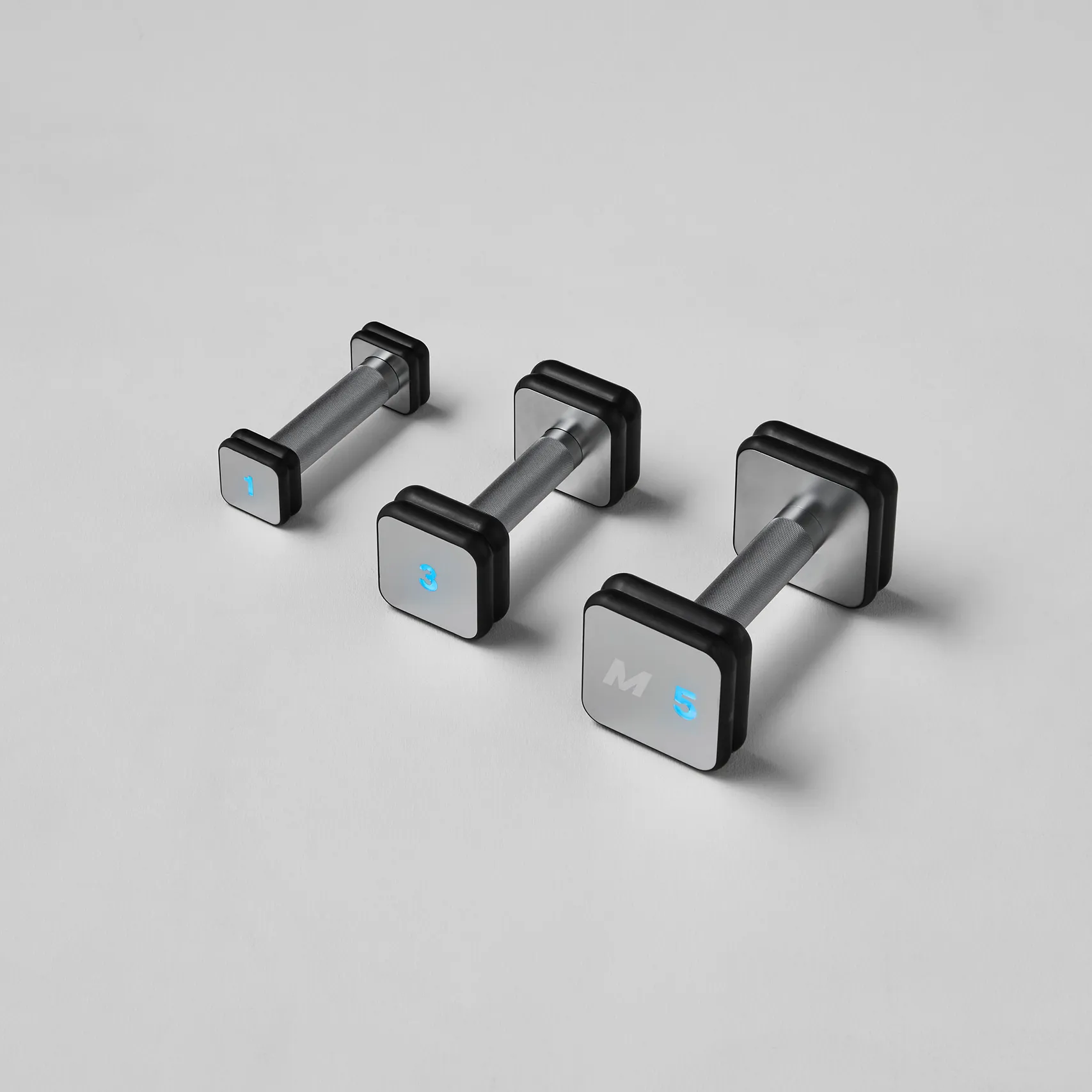 Three Mirror smart dumbbells in different weight sizes arranged on a light gray background