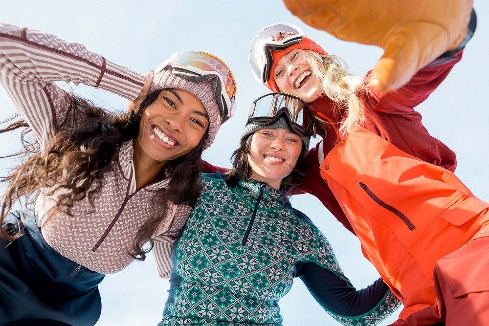 Three happy smiling women wearing skiing gear looking in the camera
