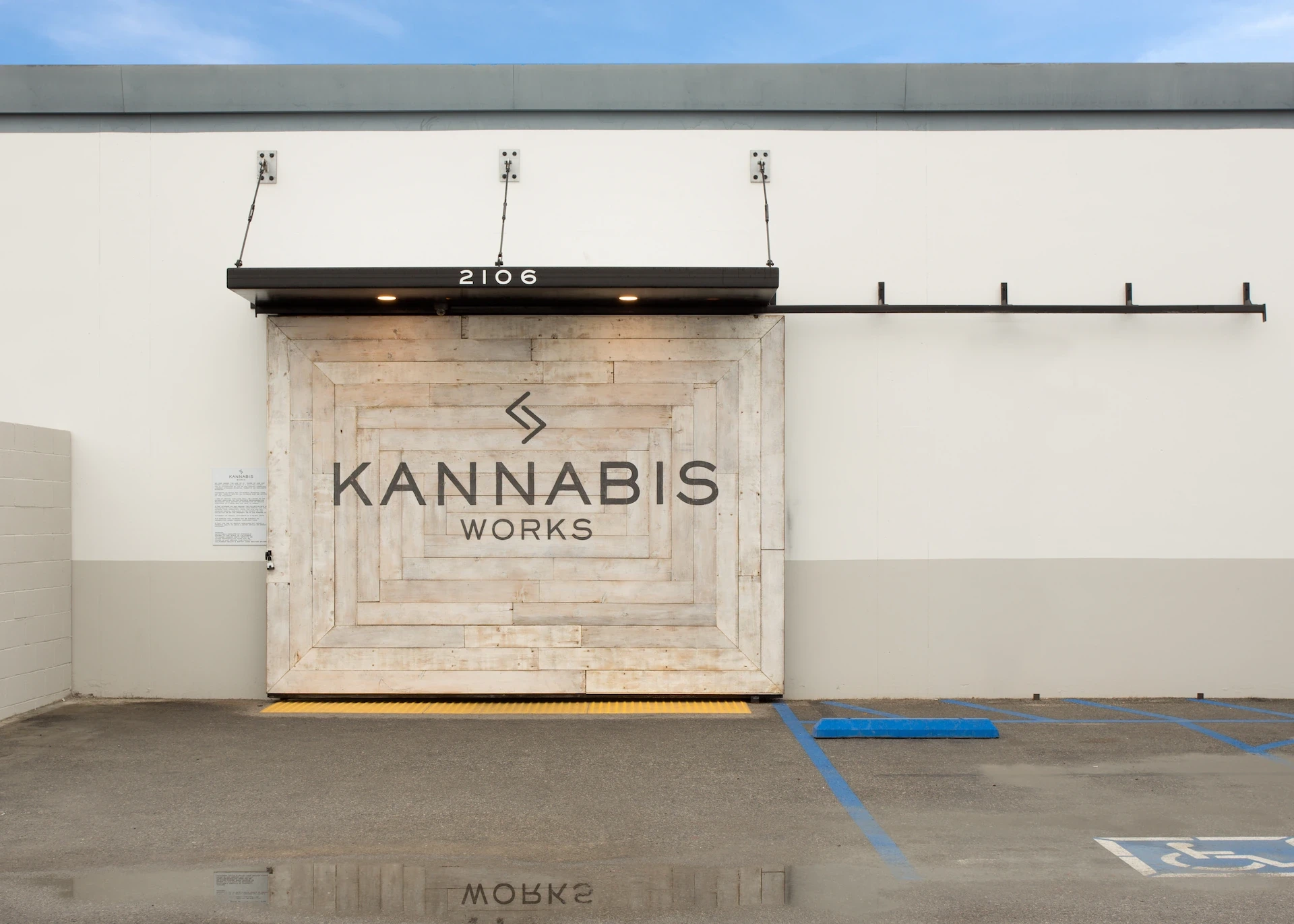 Exterior view of Kannabis Works with branded wooden facade and barn-style sliding door.